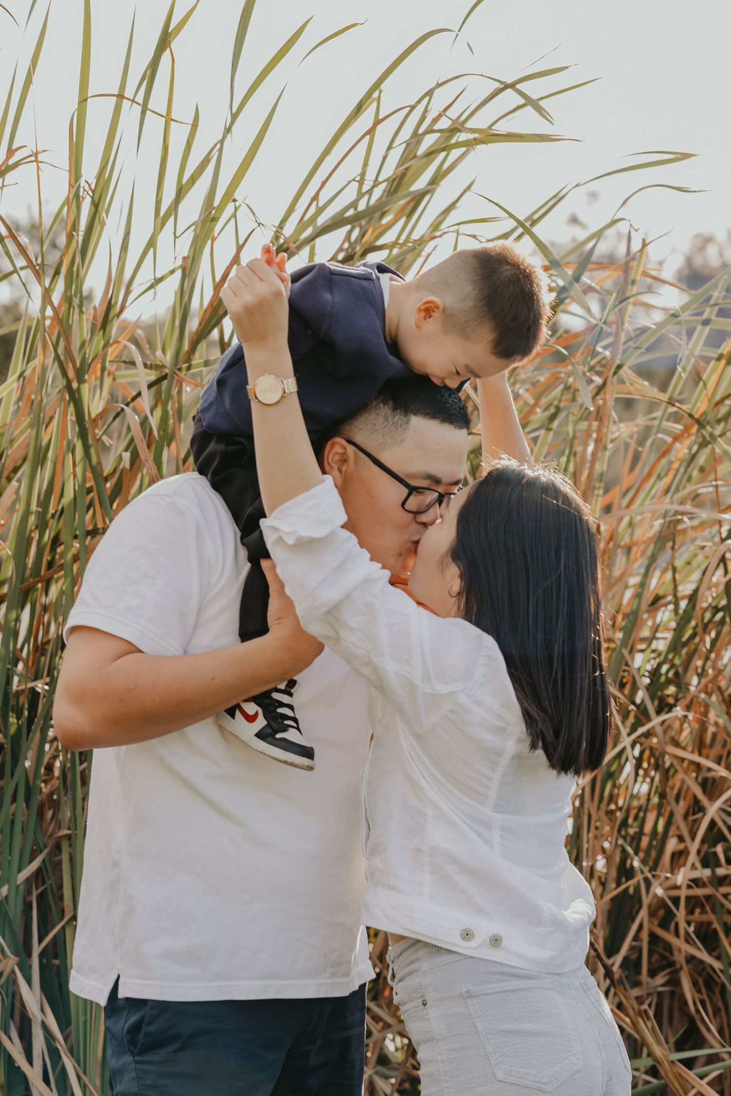 Couple hugging outdoors in tall grass, Sydney maternity photography session