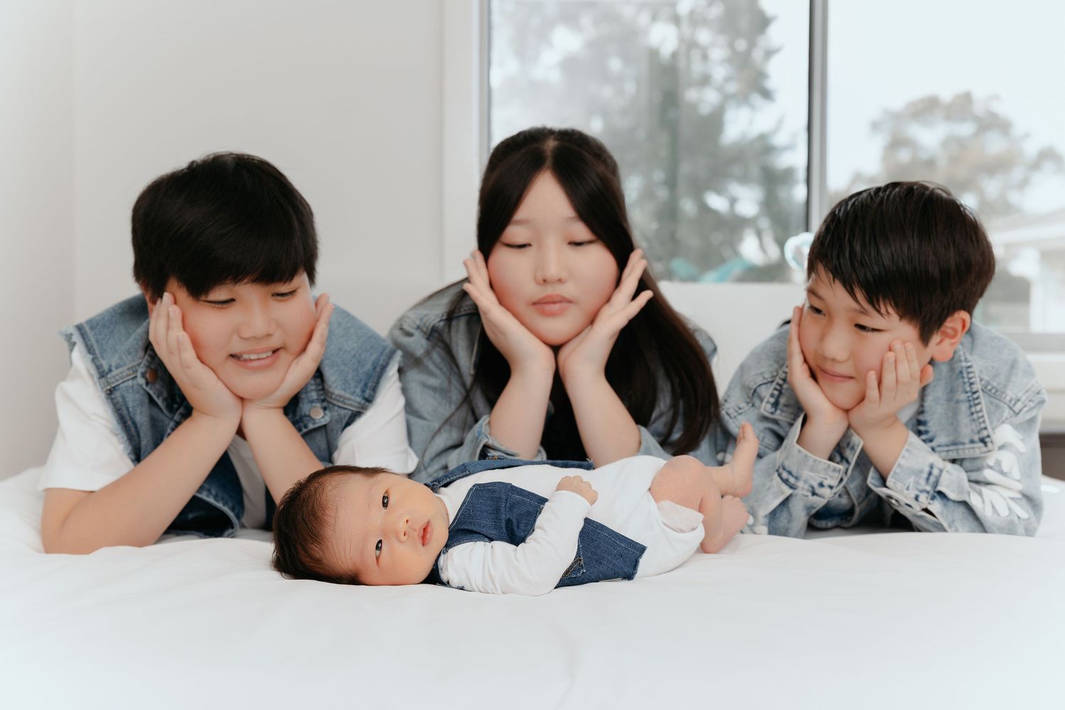 Family newborn photo with parents and siblings on a bed, at home lifestyle session Sydney