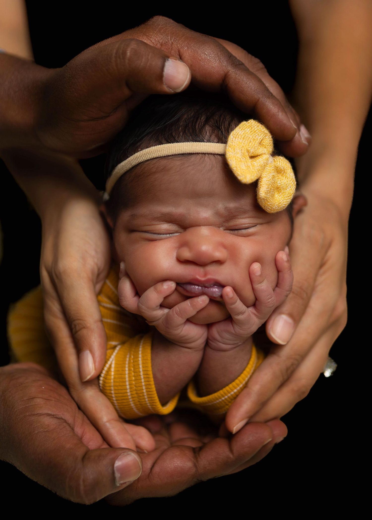 Newborn baby girl photographed being held in parents hands
