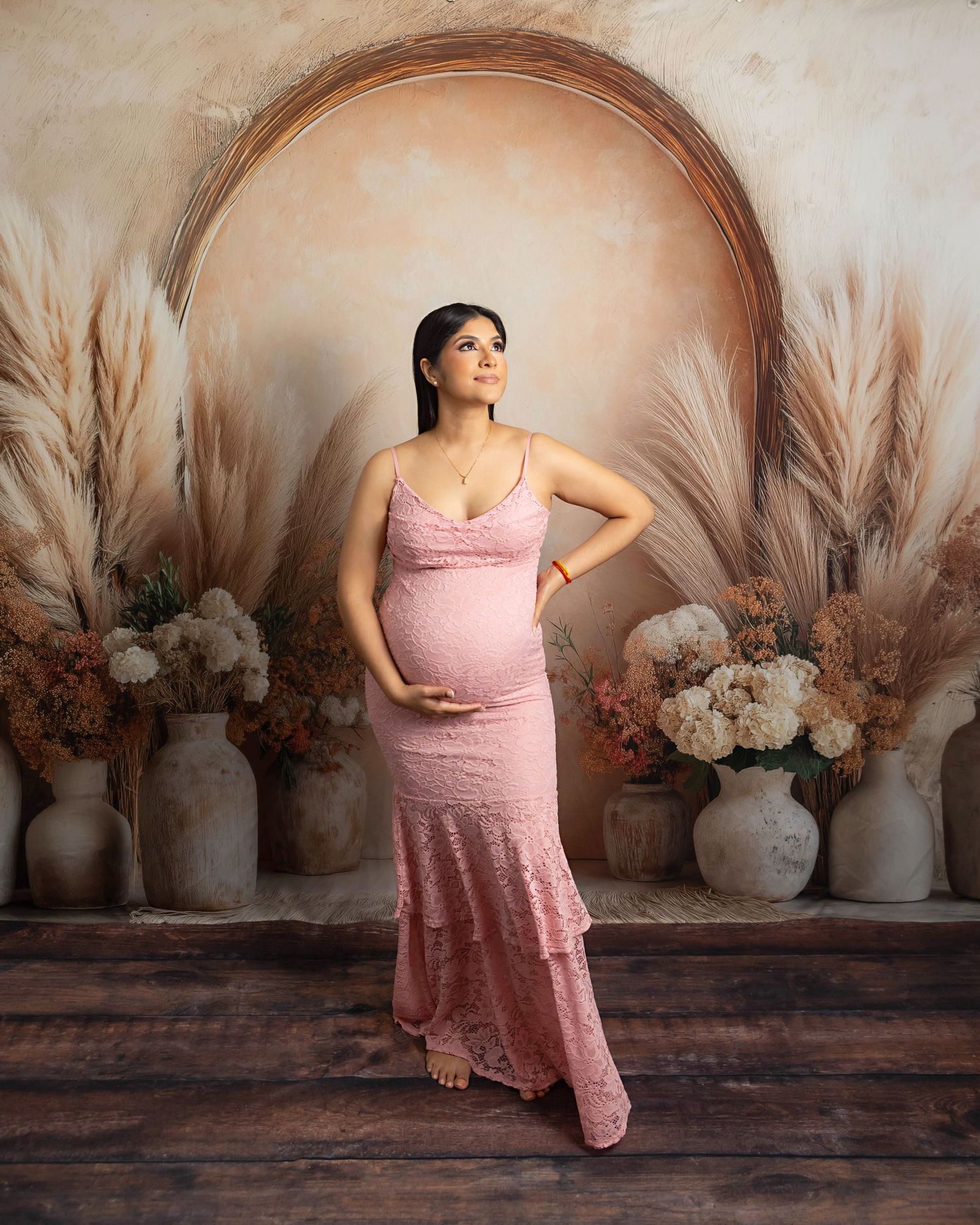 pregnant girl mom in pink dress photographed on a boho setup