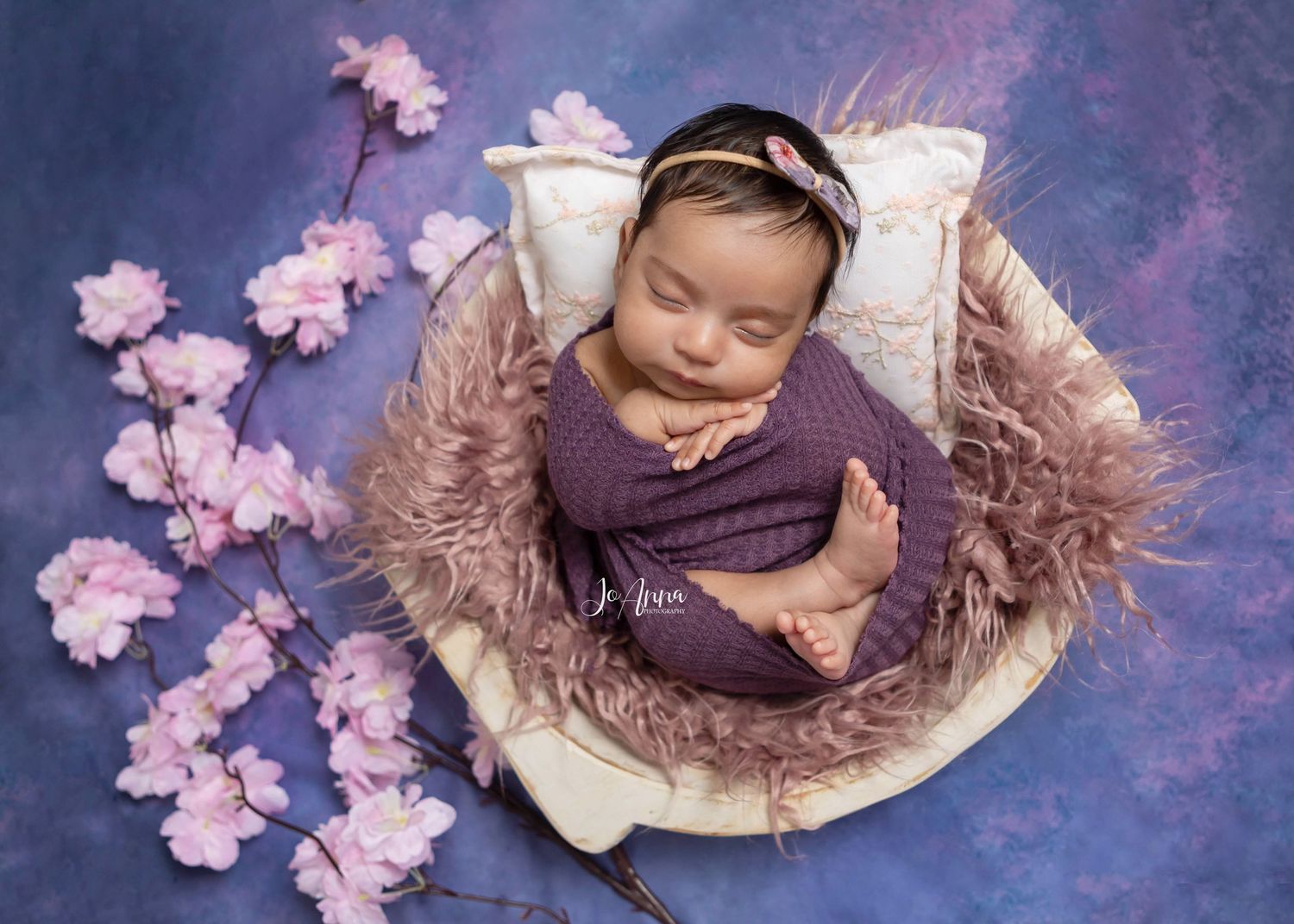 Newborn baby girl beautifully styled using pink and purple tones