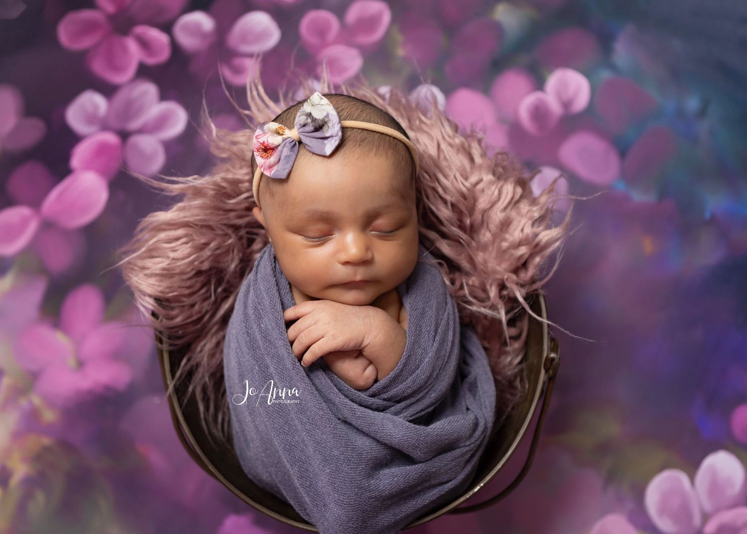 Newborn baby girl beautifully styled in using pink and purple tones
