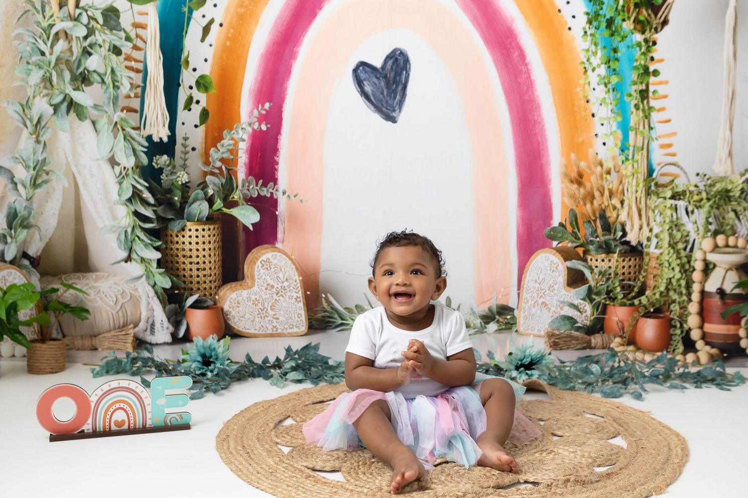Baby girl posing in front of a boho rainbow themed set