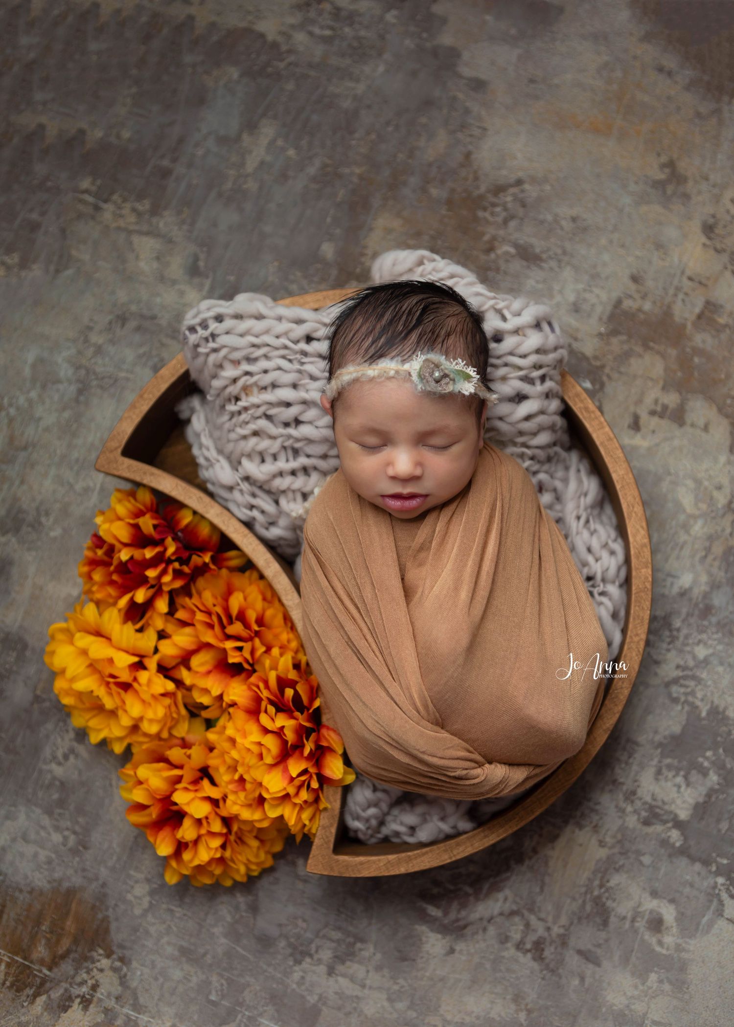 Newborn baby girl beautifully styled using brown and orange tones.