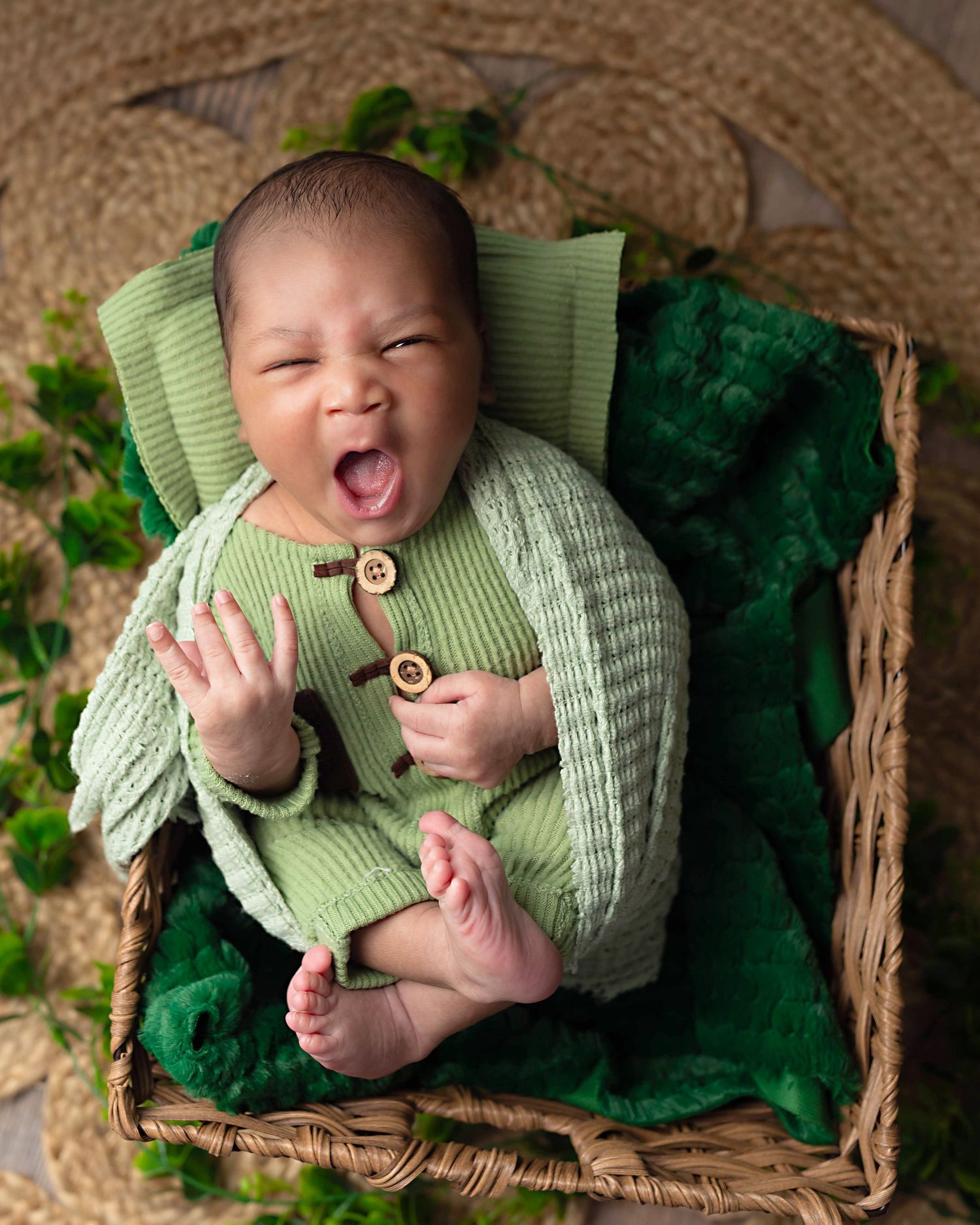 Yawning newborn baby beautifully styled in studio props
