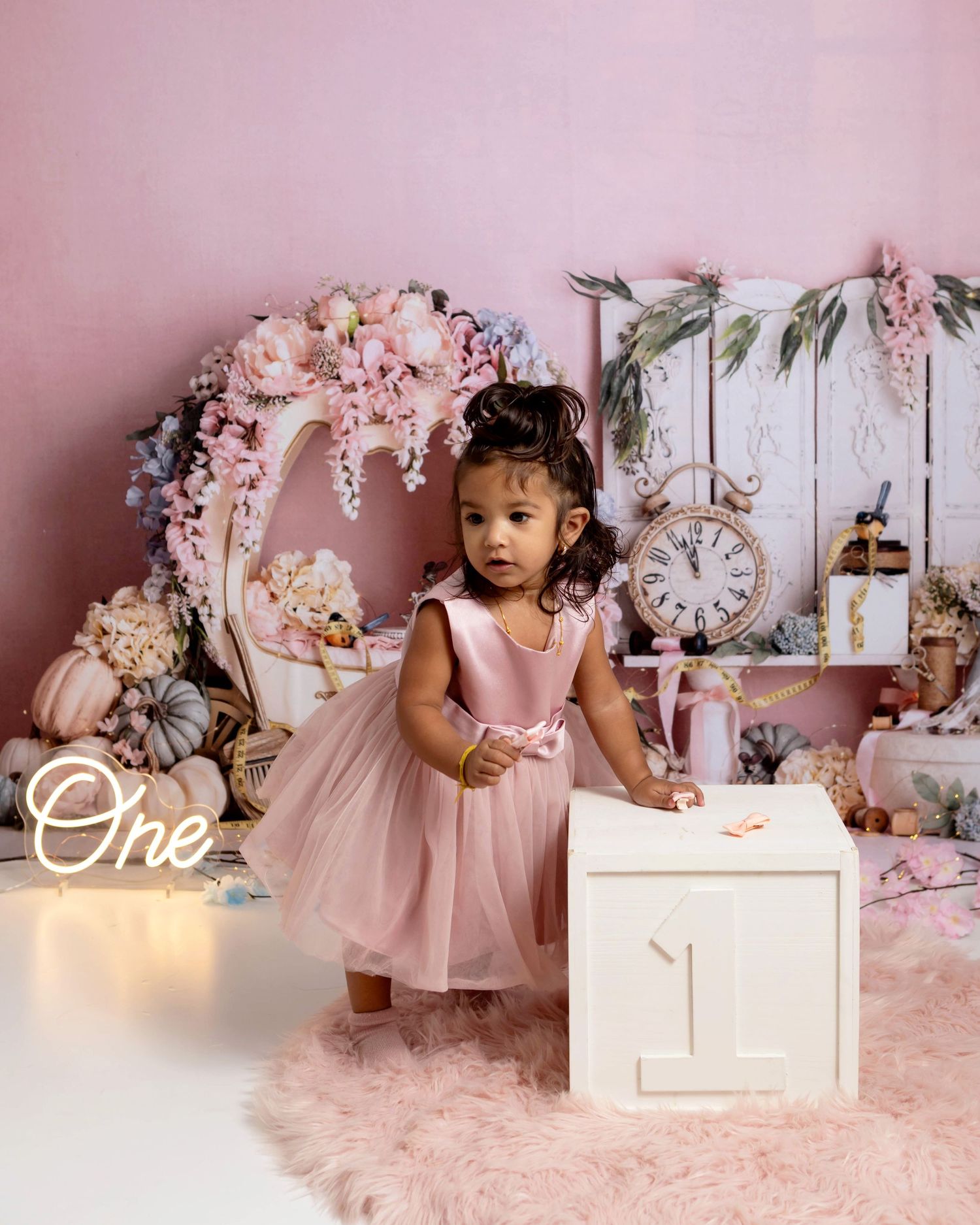Princess themed birthday session with baby girl standing next to a white box