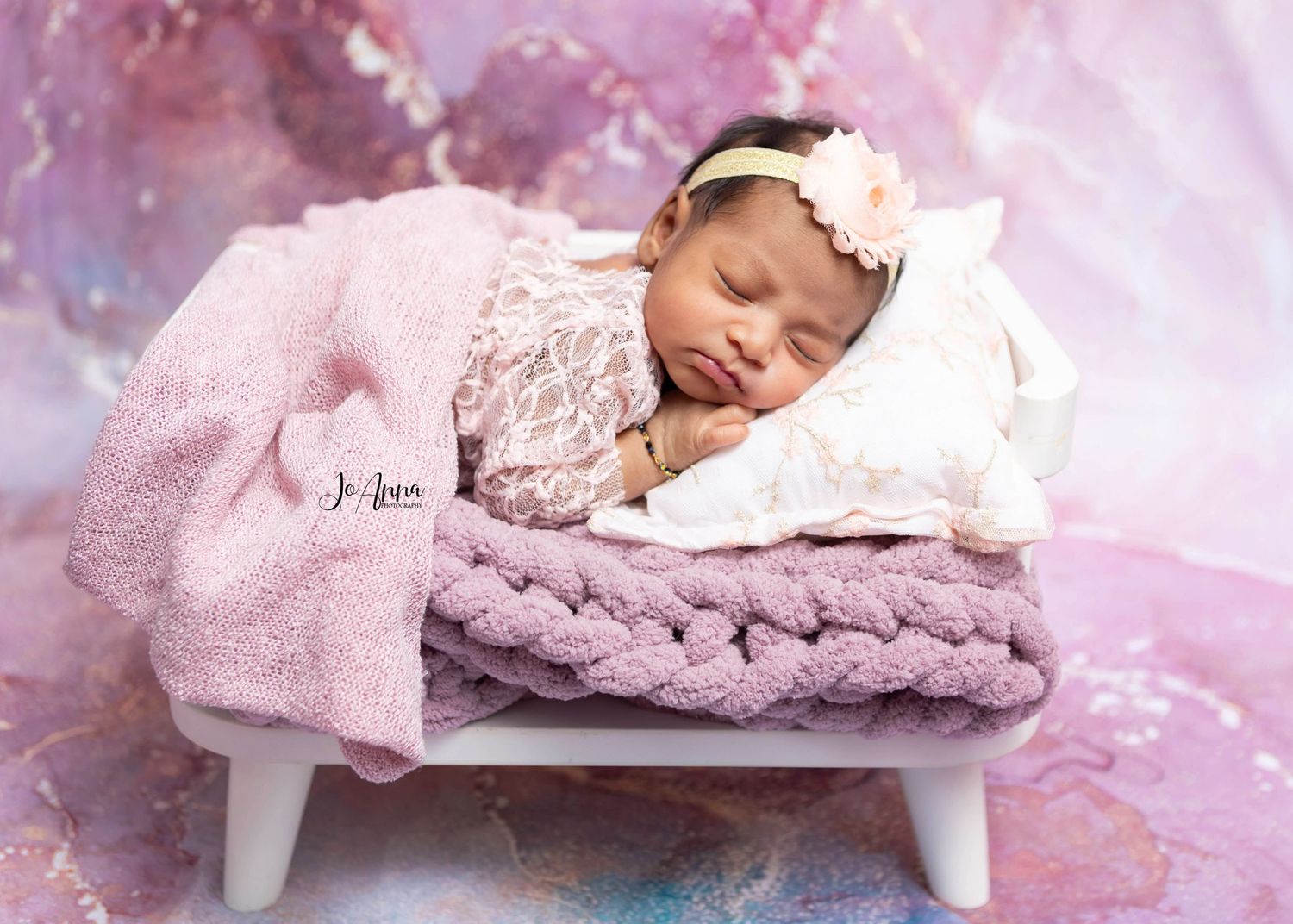 Newborn baby girl beautifully styled in using pink and purple tones