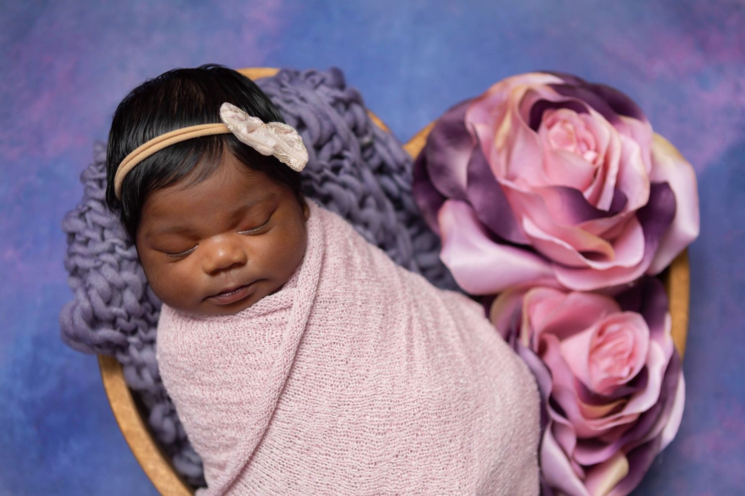 Newborn baby girl beautifully styled in using pink and purple tones