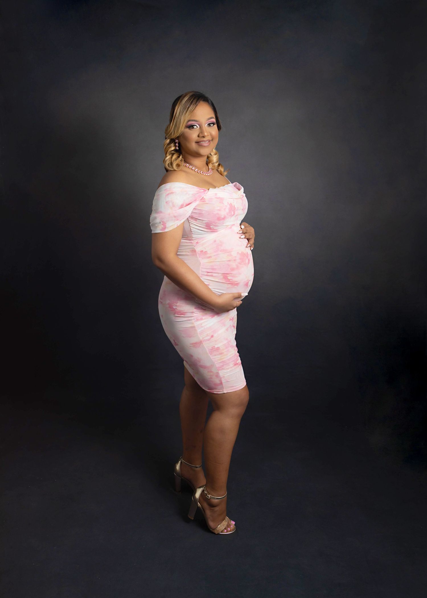 Pregnant girl mom cradling her bump with a classic charcoal backdrop