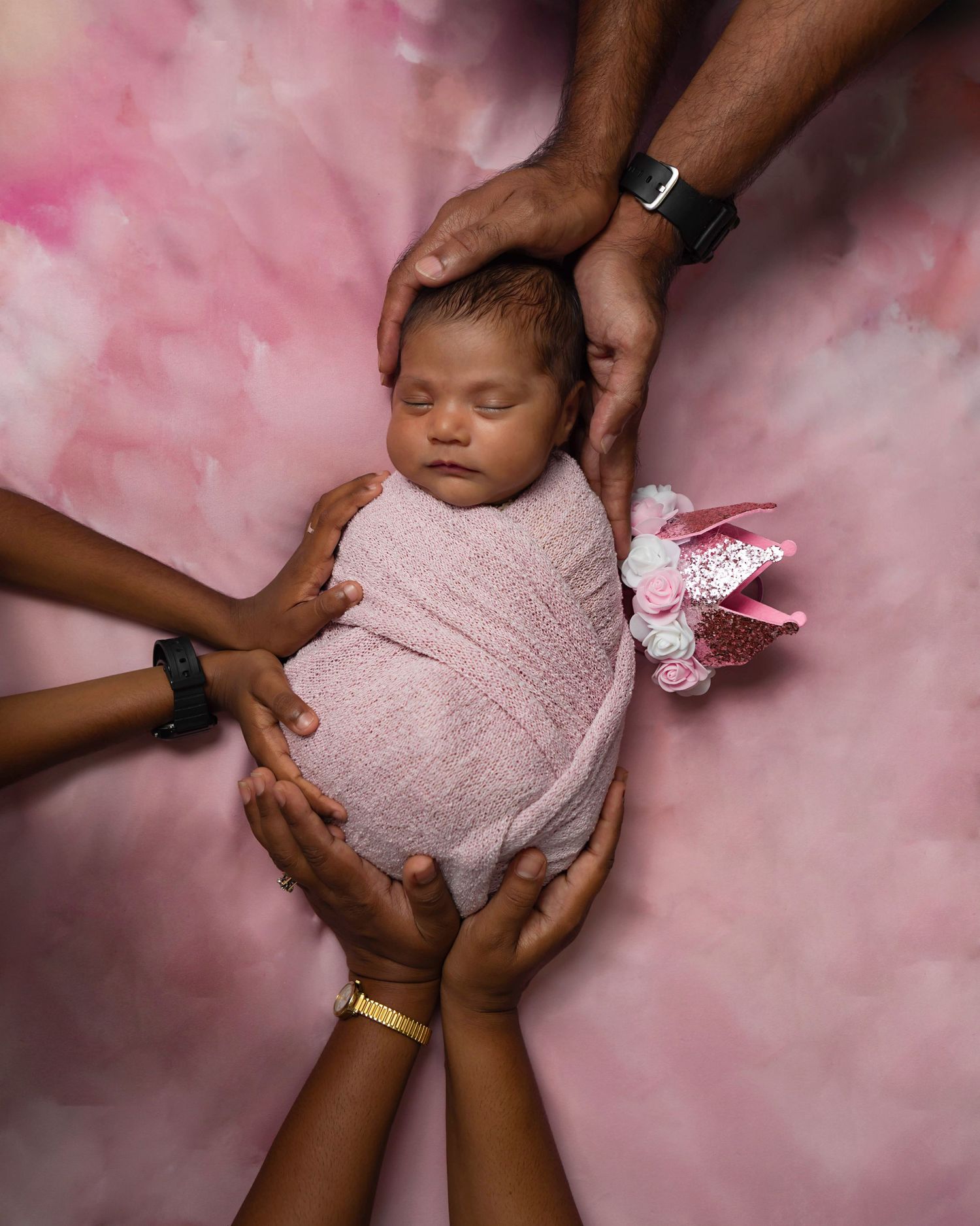 Newborn baby girl photographed being held in parents hands