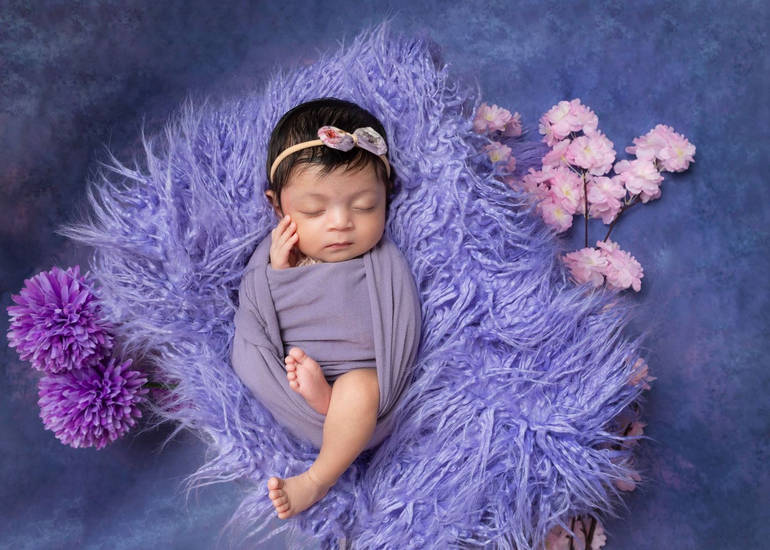 Newborn baby girl beautifully styled in using pink and purple tones