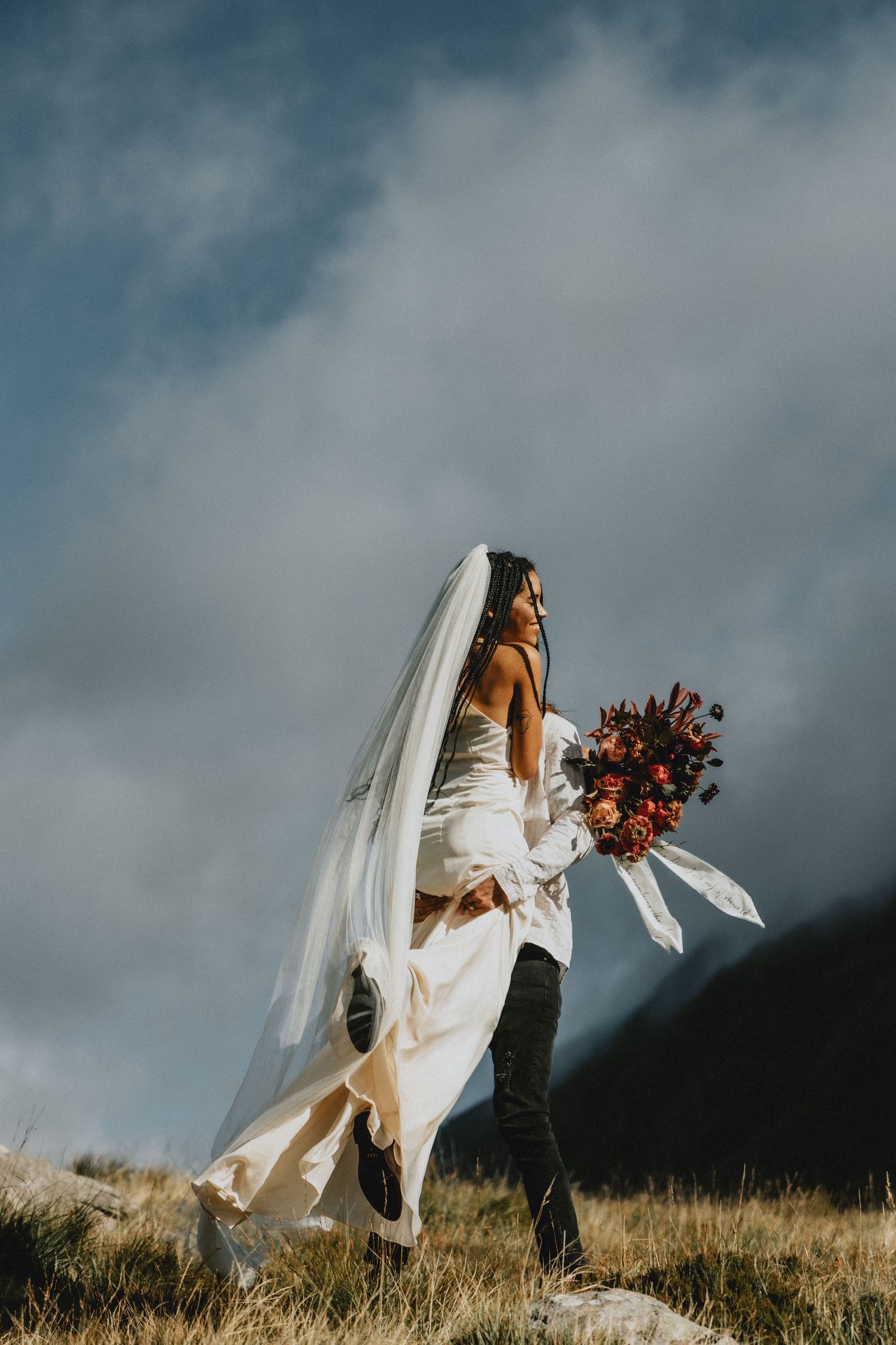 Couple embracing during an intimate elopement in North Wales with mountains in the background, photographed in a natural documentary style.