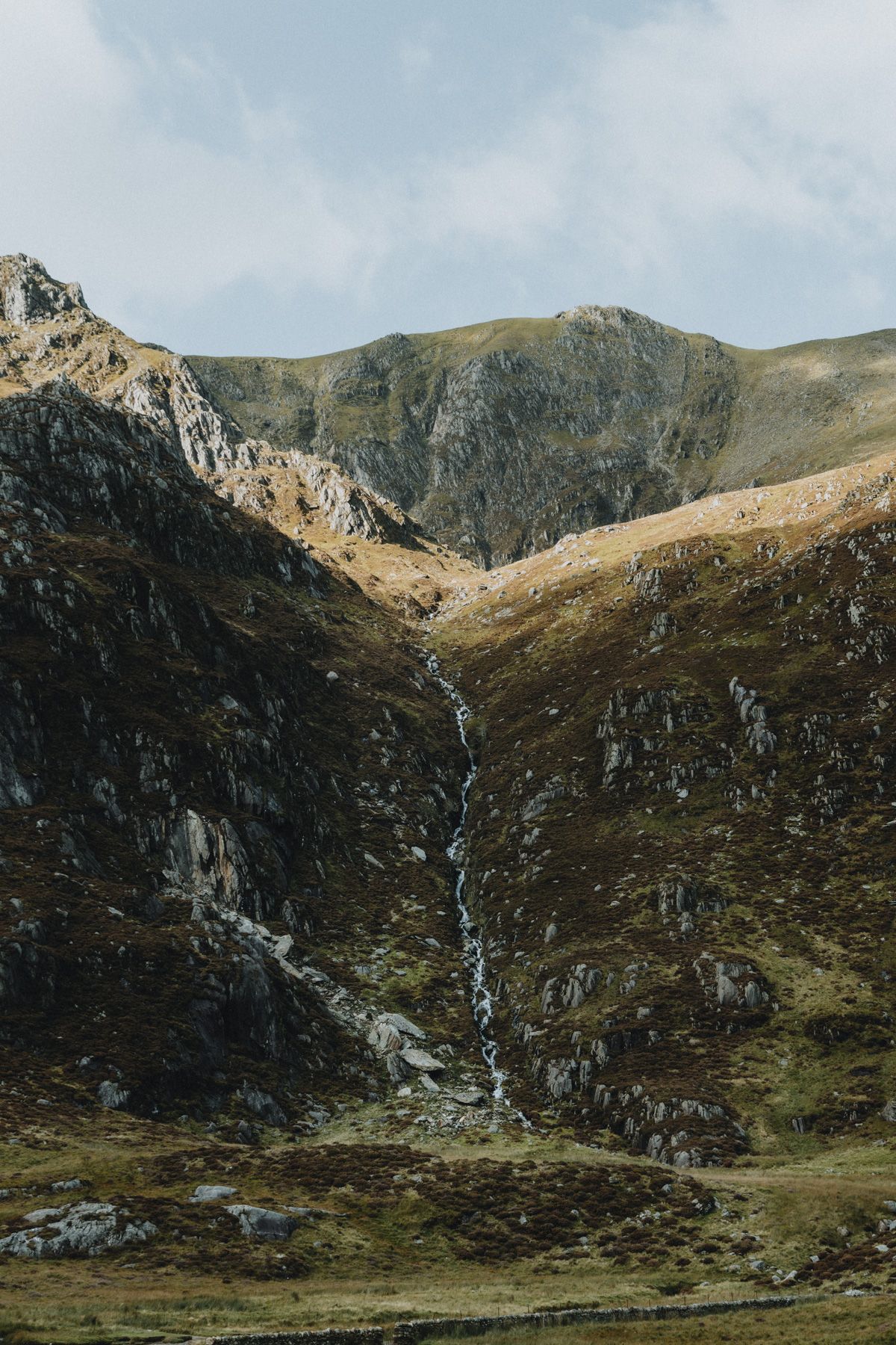 Couple embracing during an intimate elopement in North Wales with mountains in the background, photographed in a nature