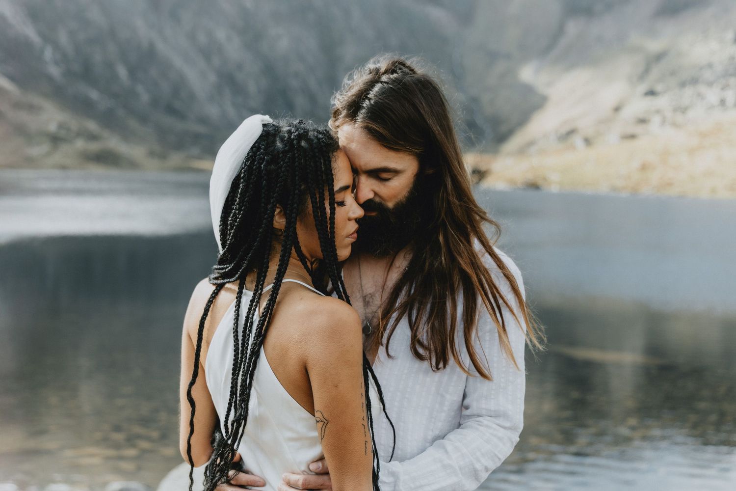 Couple embracing during an intimate elopement in North Wales with mountains in the background, photographed in a natural documentary style.