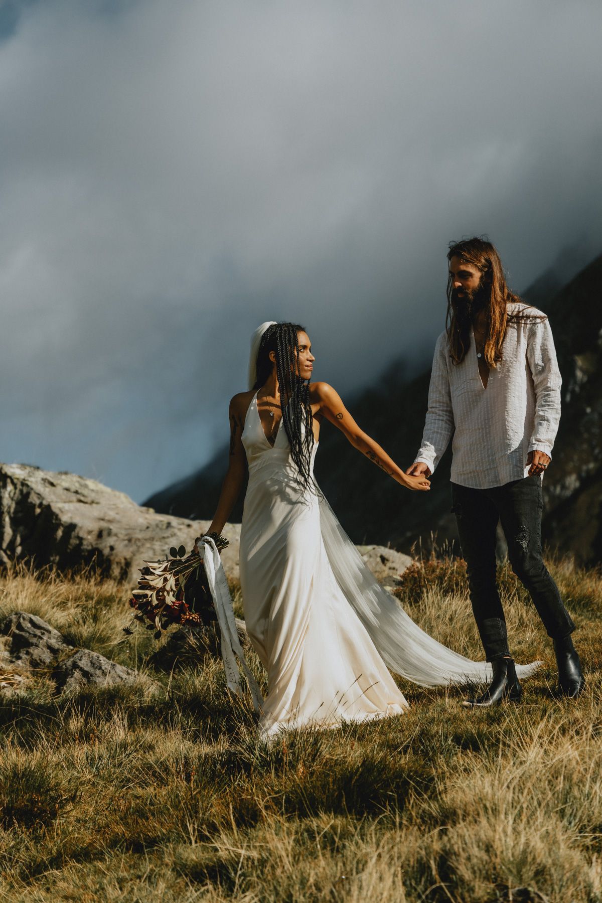Couple embracing during an intimate elopement in North Wales with mountains in the background, photographed in a natural documentary style.