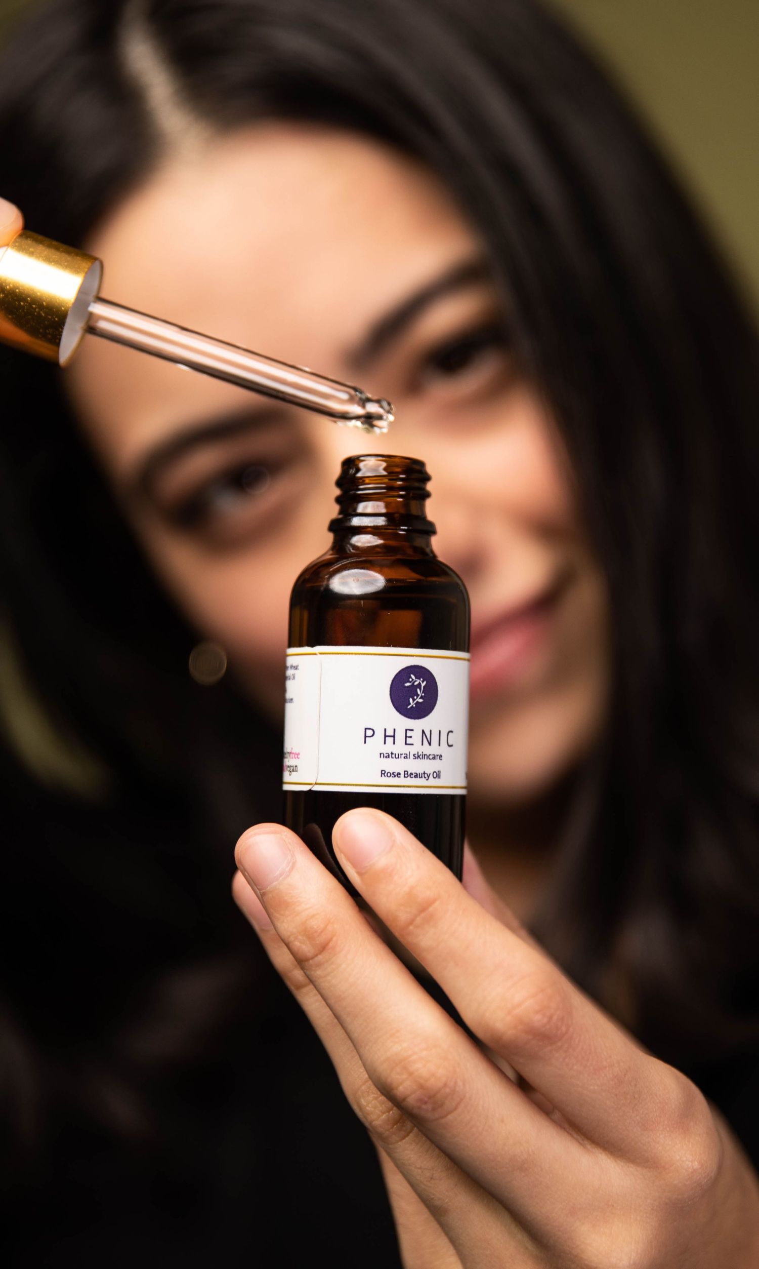 Close-up shots of hands holding glass dropper bottle labeled Phenic against dark background.