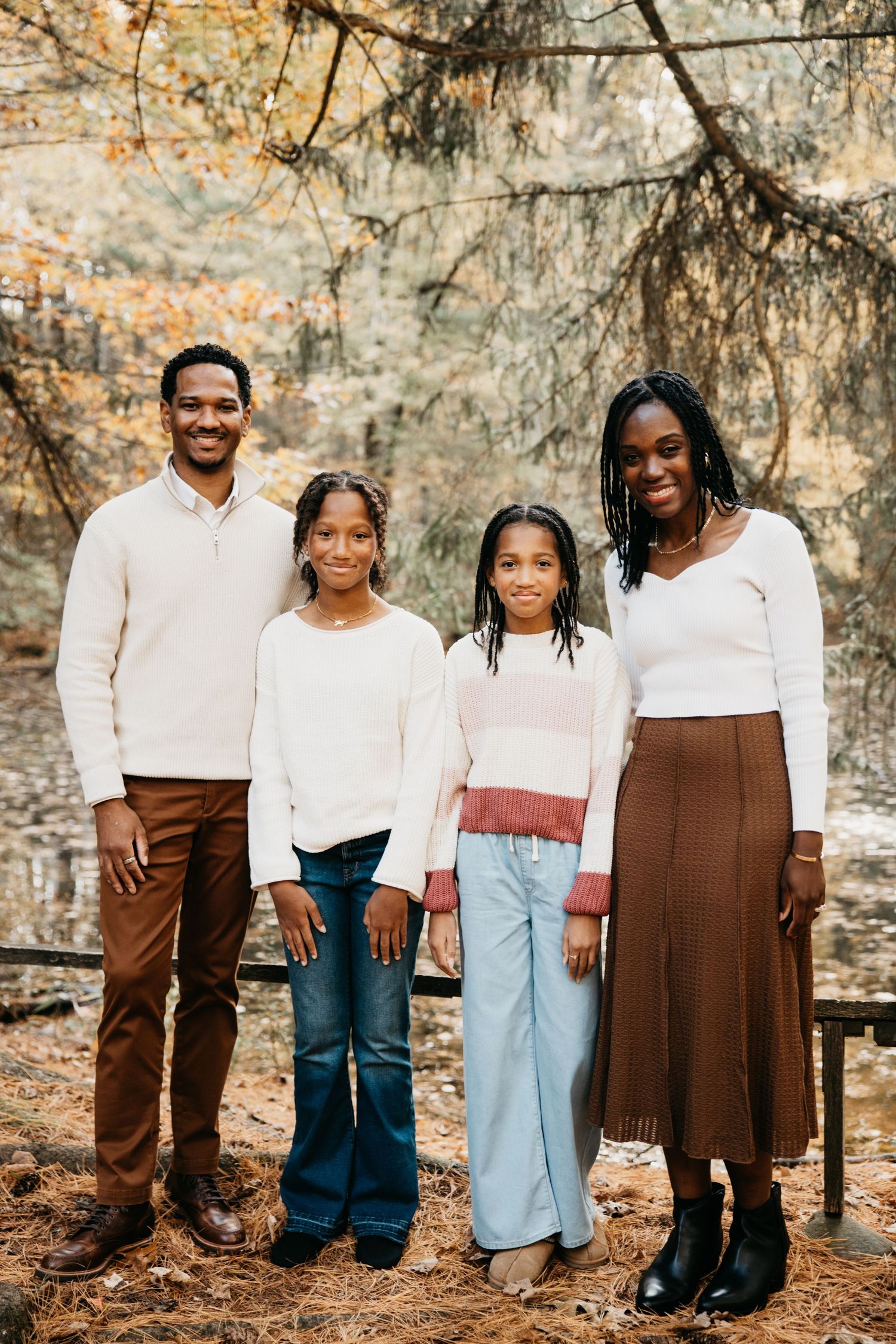 Family group photo showing coordinated outfits of white tops and brown or blue bottoms in a forest setting.