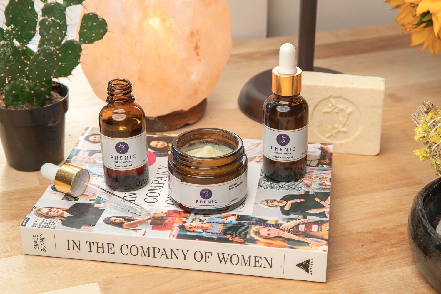 Wellness products displayed with books, salt lamp and cactus on wooden surface.