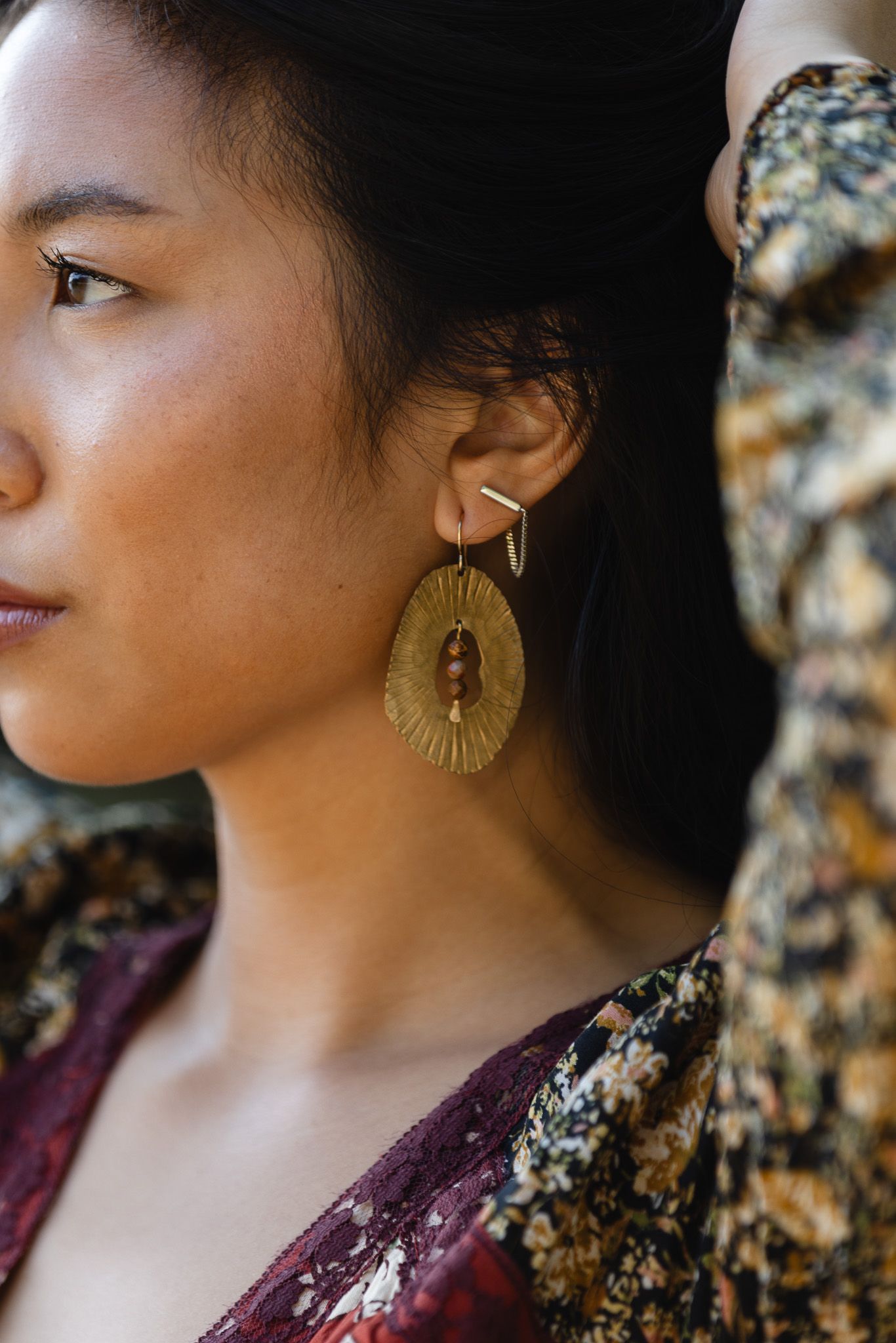 Profile view showcasing gold statement earrings against a dark background.