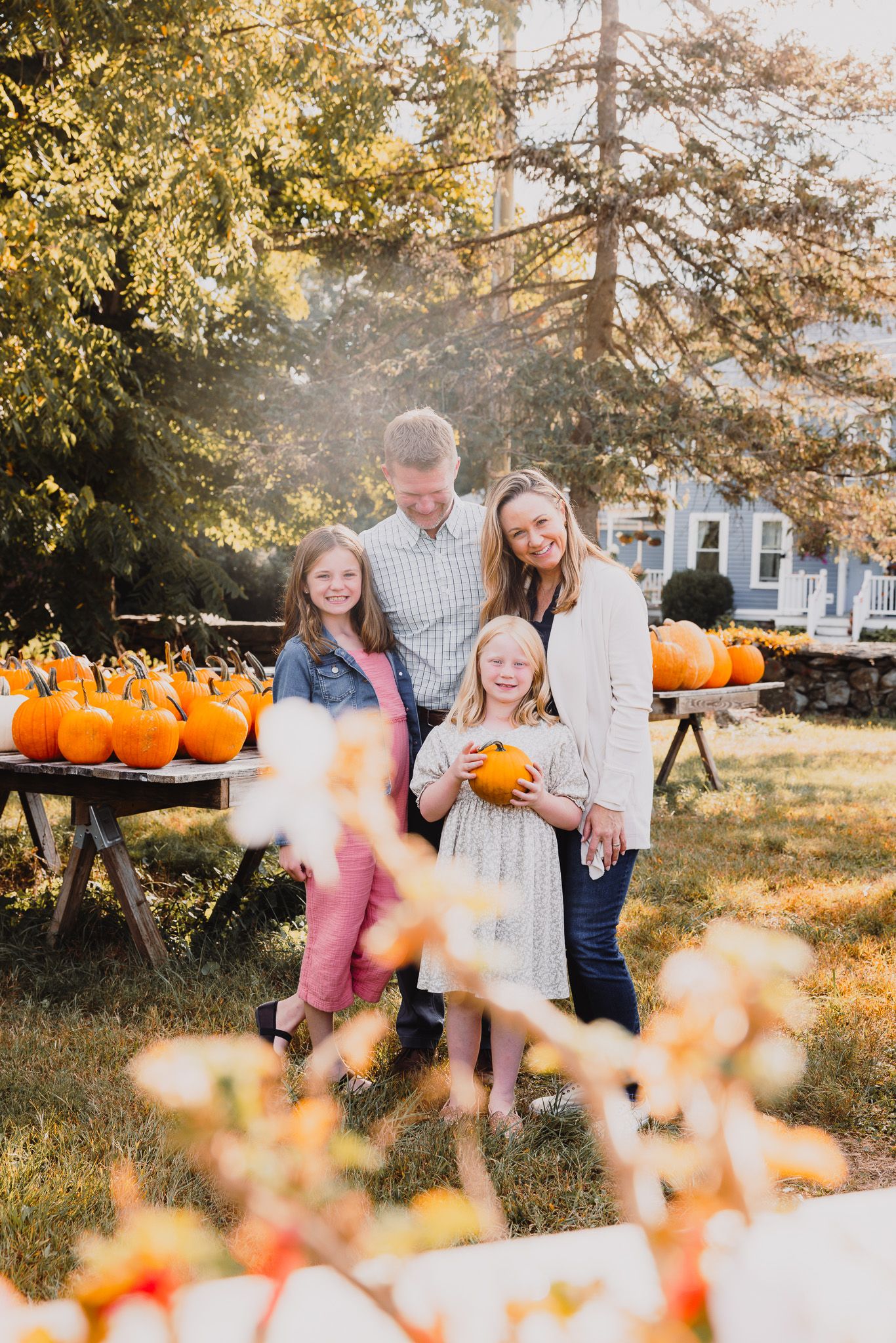 Family gathering around pumpkins during autumn golden hour.
