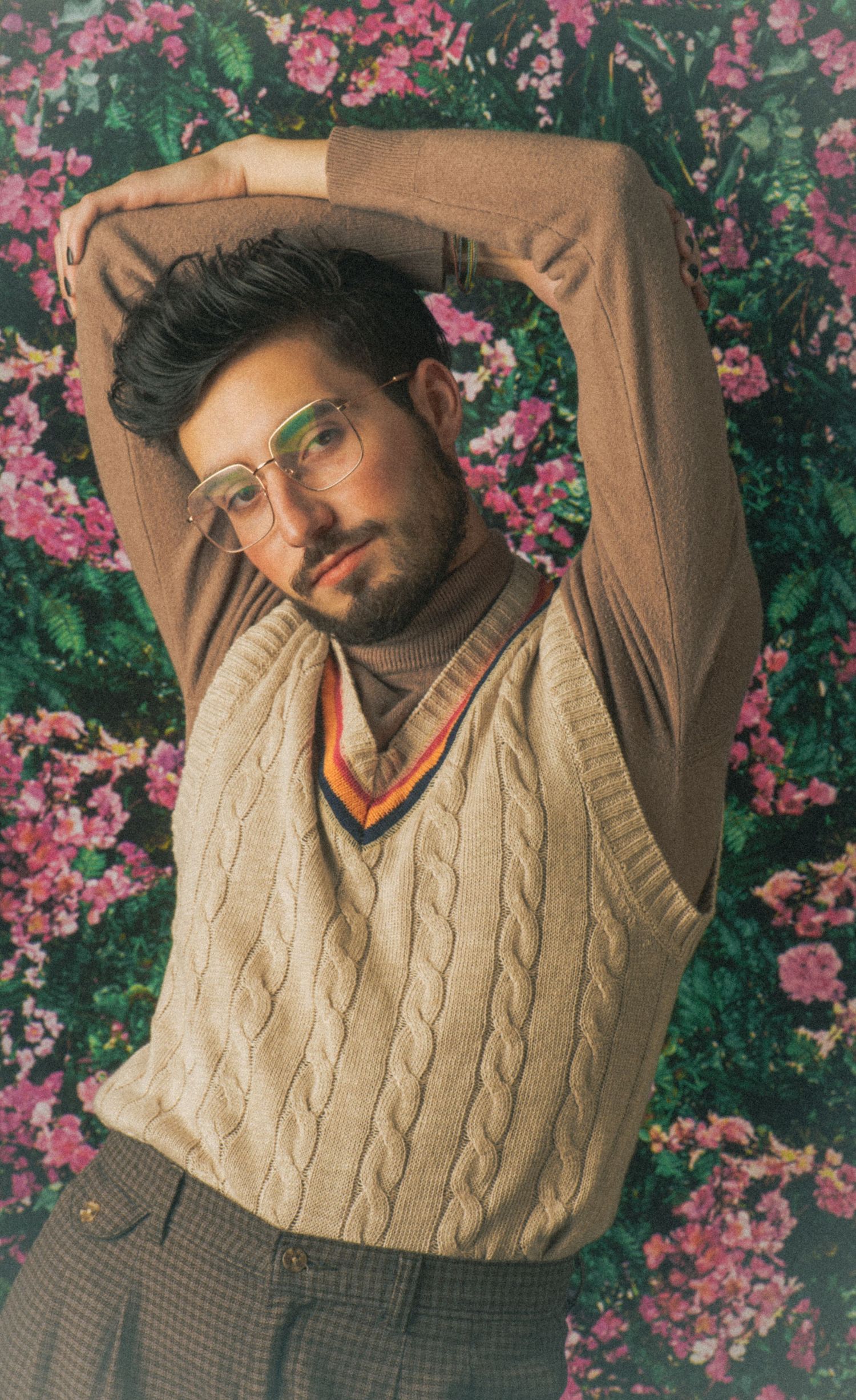 Retro style portraits showing cream cable knit vest against blooming pink flowers.
