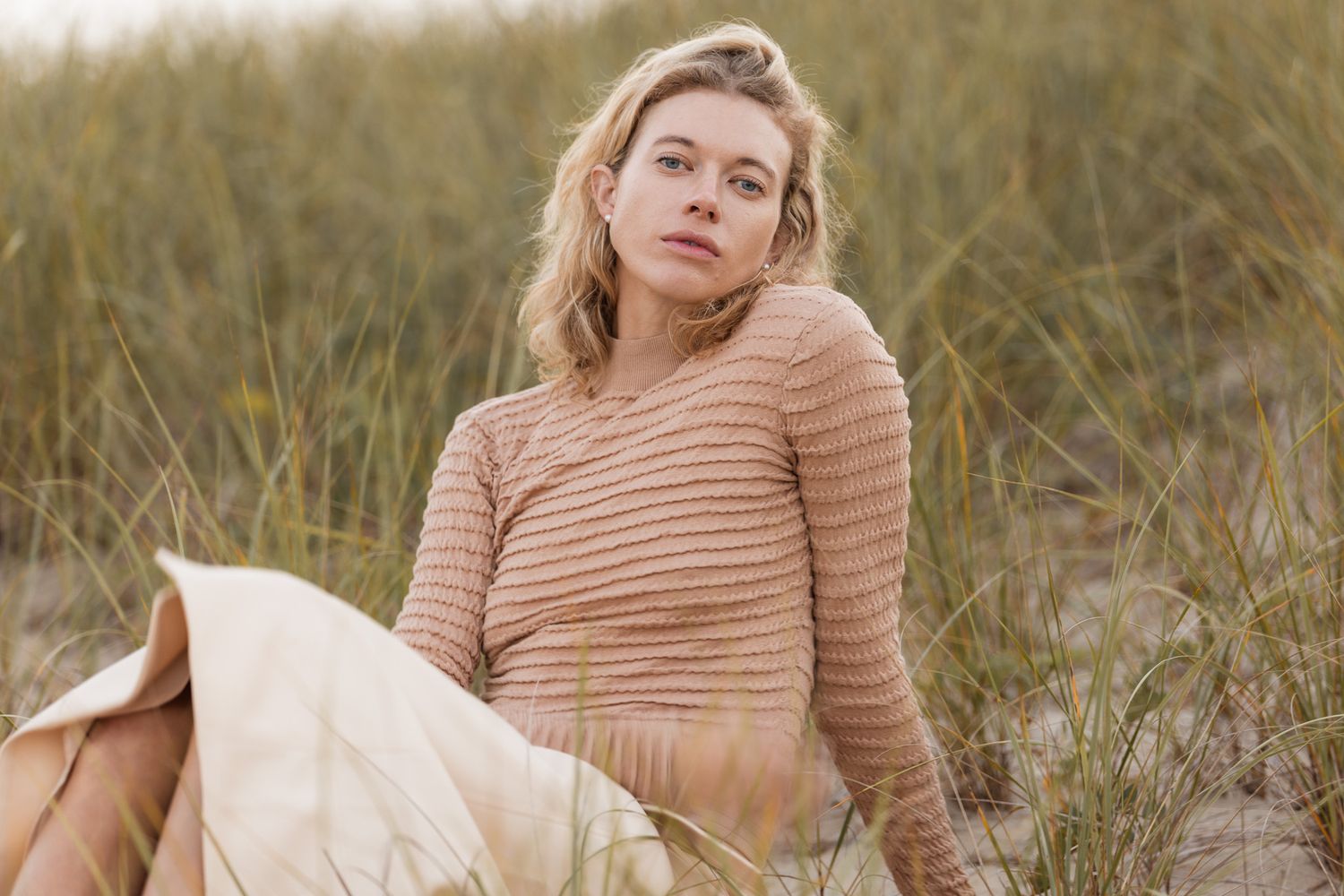 Beach photography session in striped peach sweater among coastal grass.