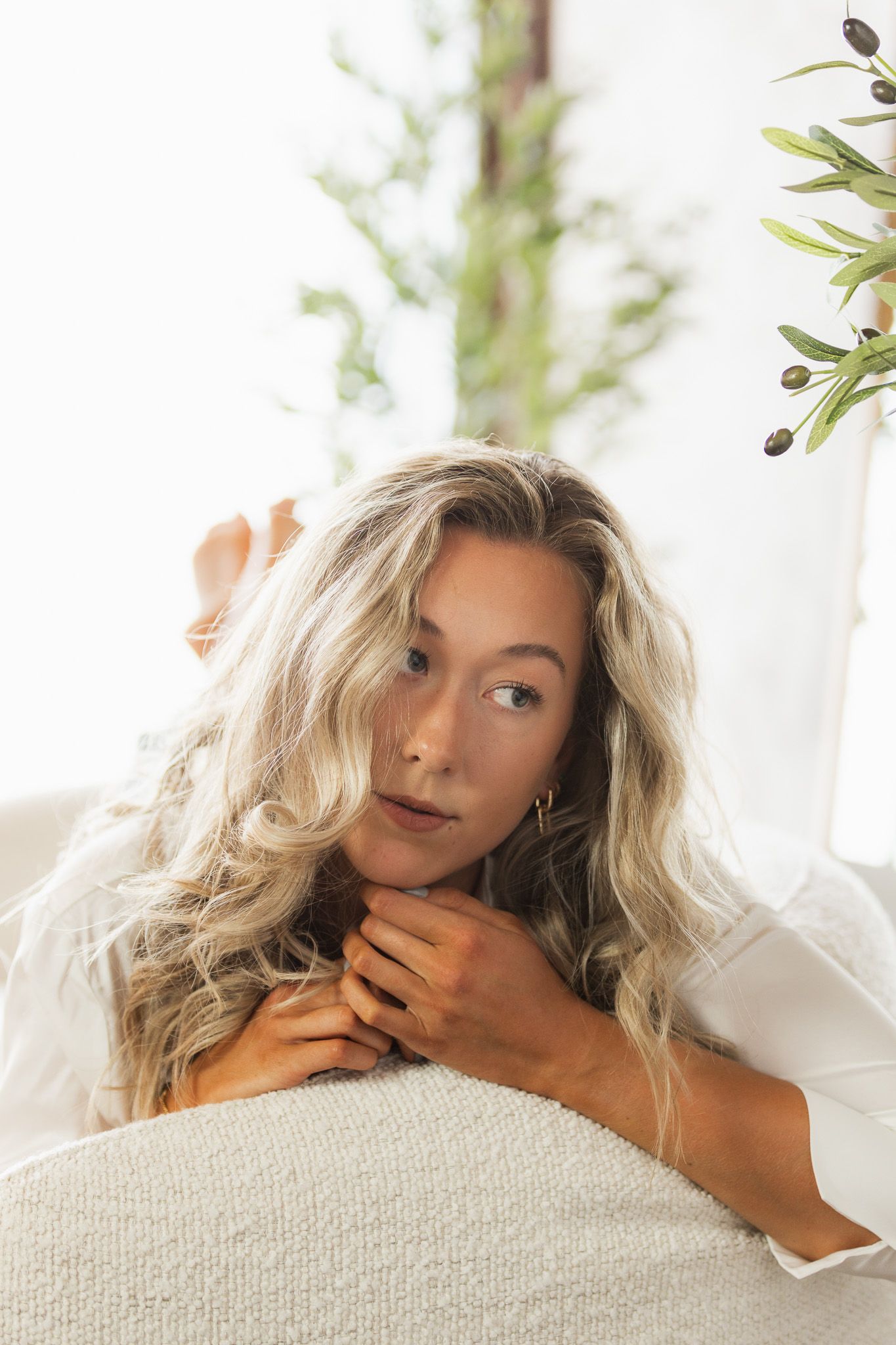 Artistic boudoir photography with soft lighting and white bedding.