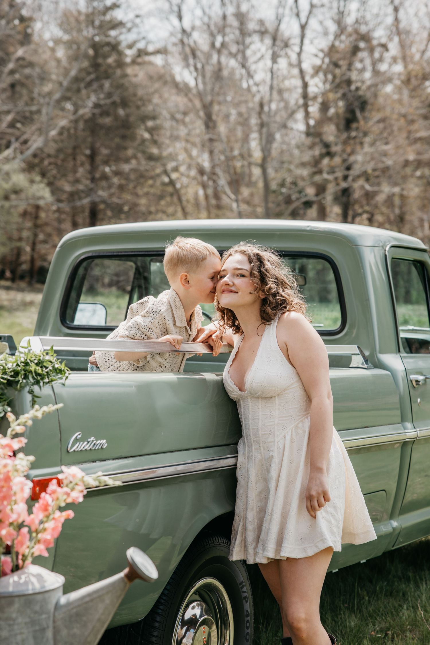Couple sharing a romantic moment leaning against a vintage green pickup truck outdoors in spring.
