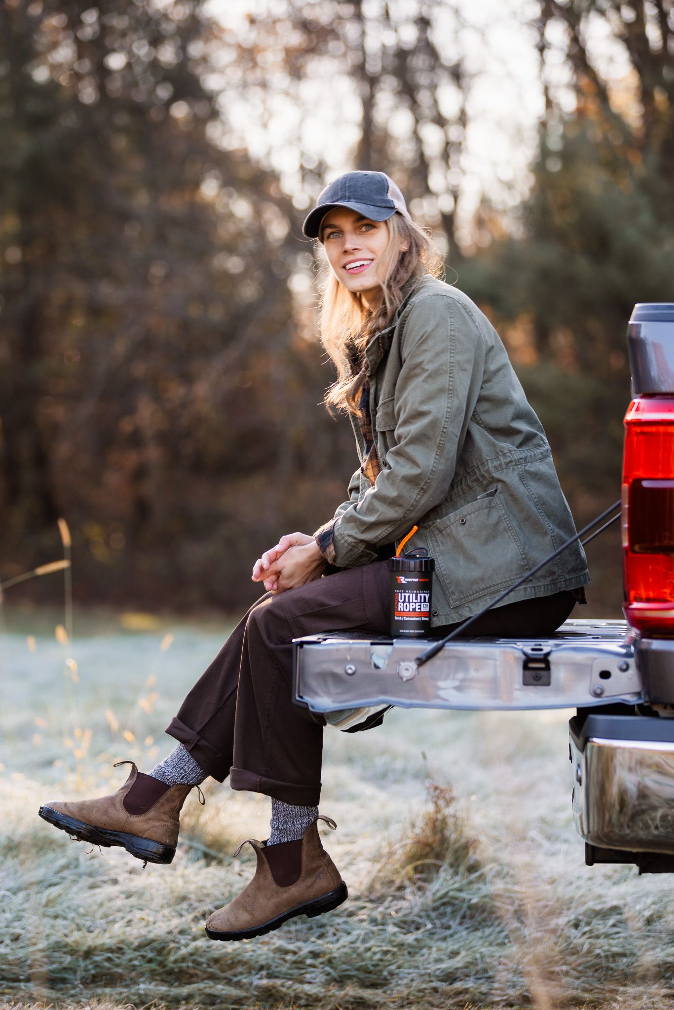 Person sitting on truck tailgate in casual outdoor wear during golden hour.