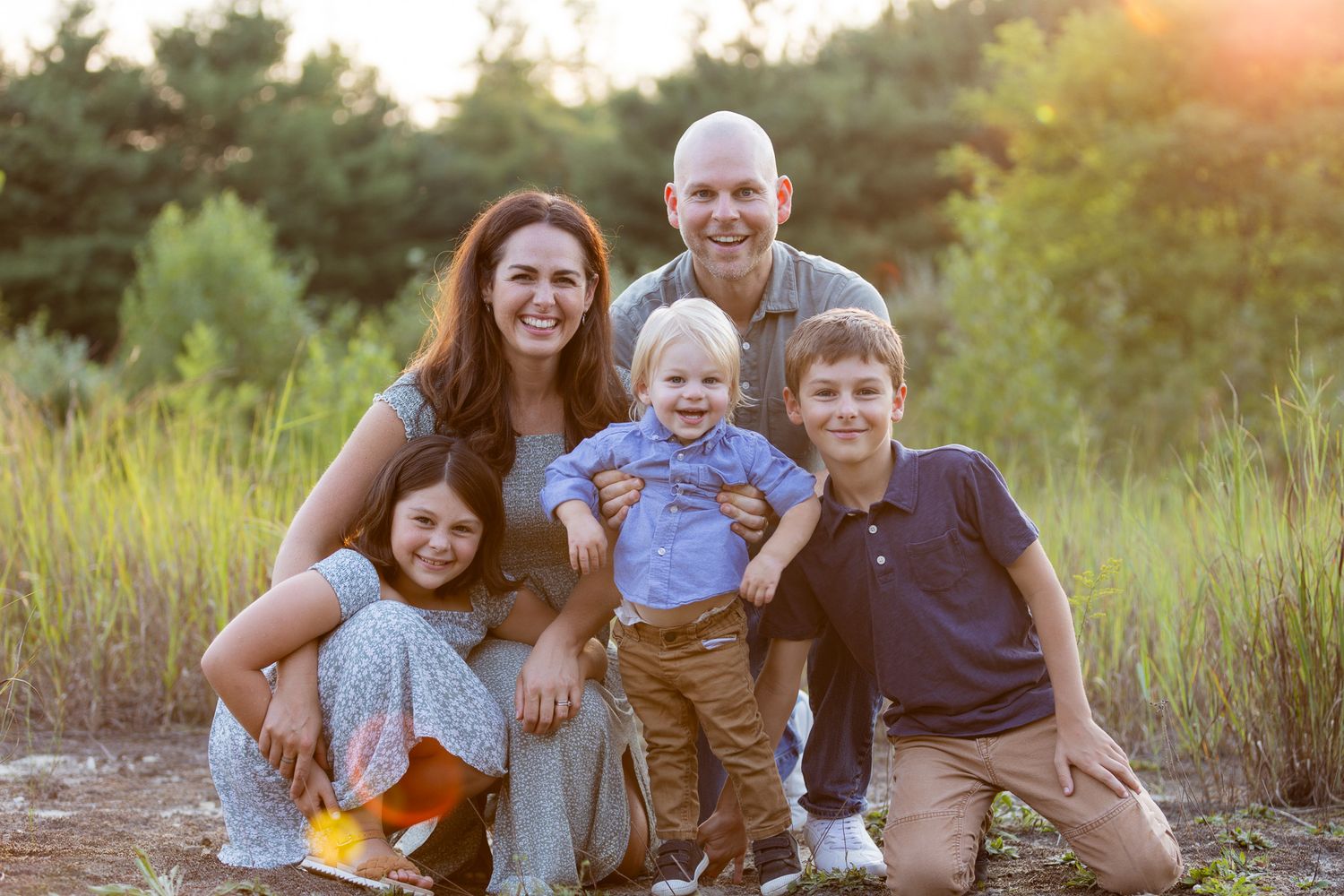 Family group poses playfully together during golden hour photo session outdoors.