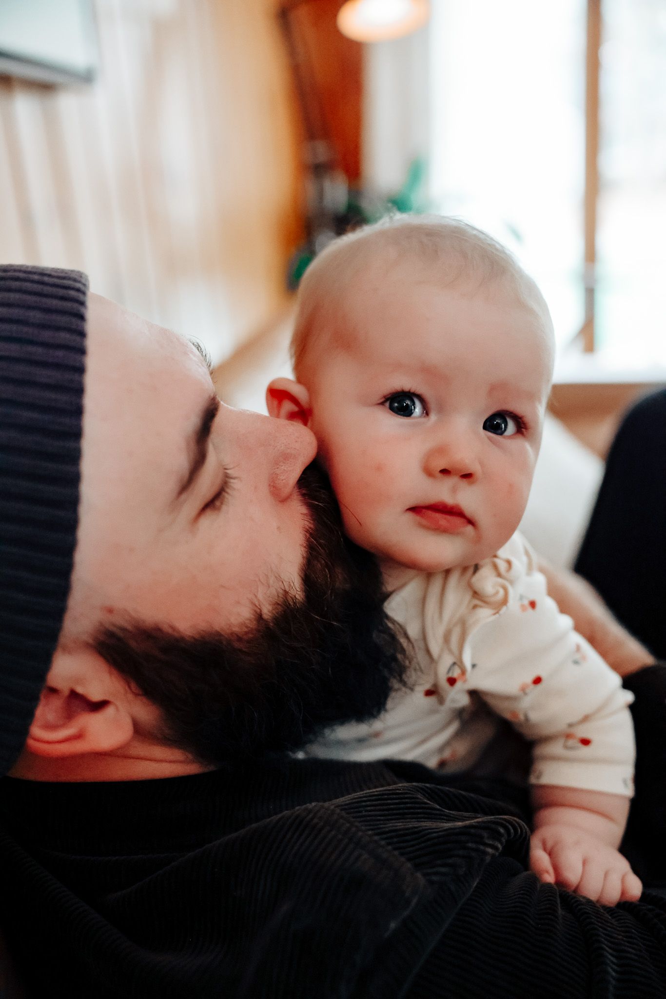 Sweet tender moment showing parent and baby bonding with gentle affection indoors.