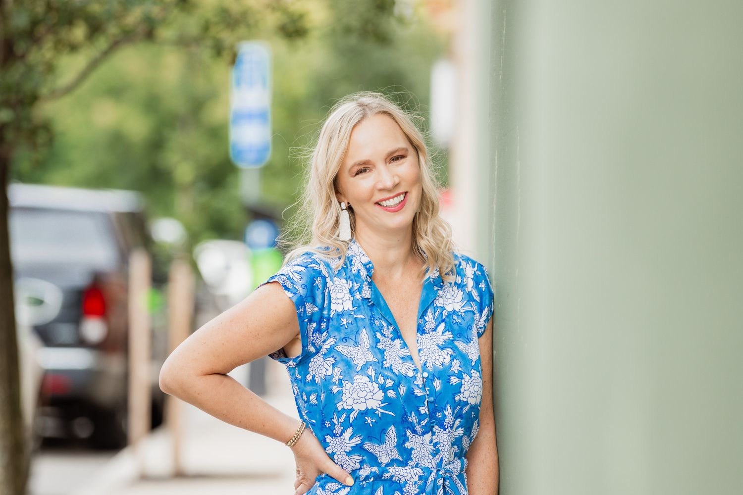 Urban lifestyle photography with green columns and blue floral dress.