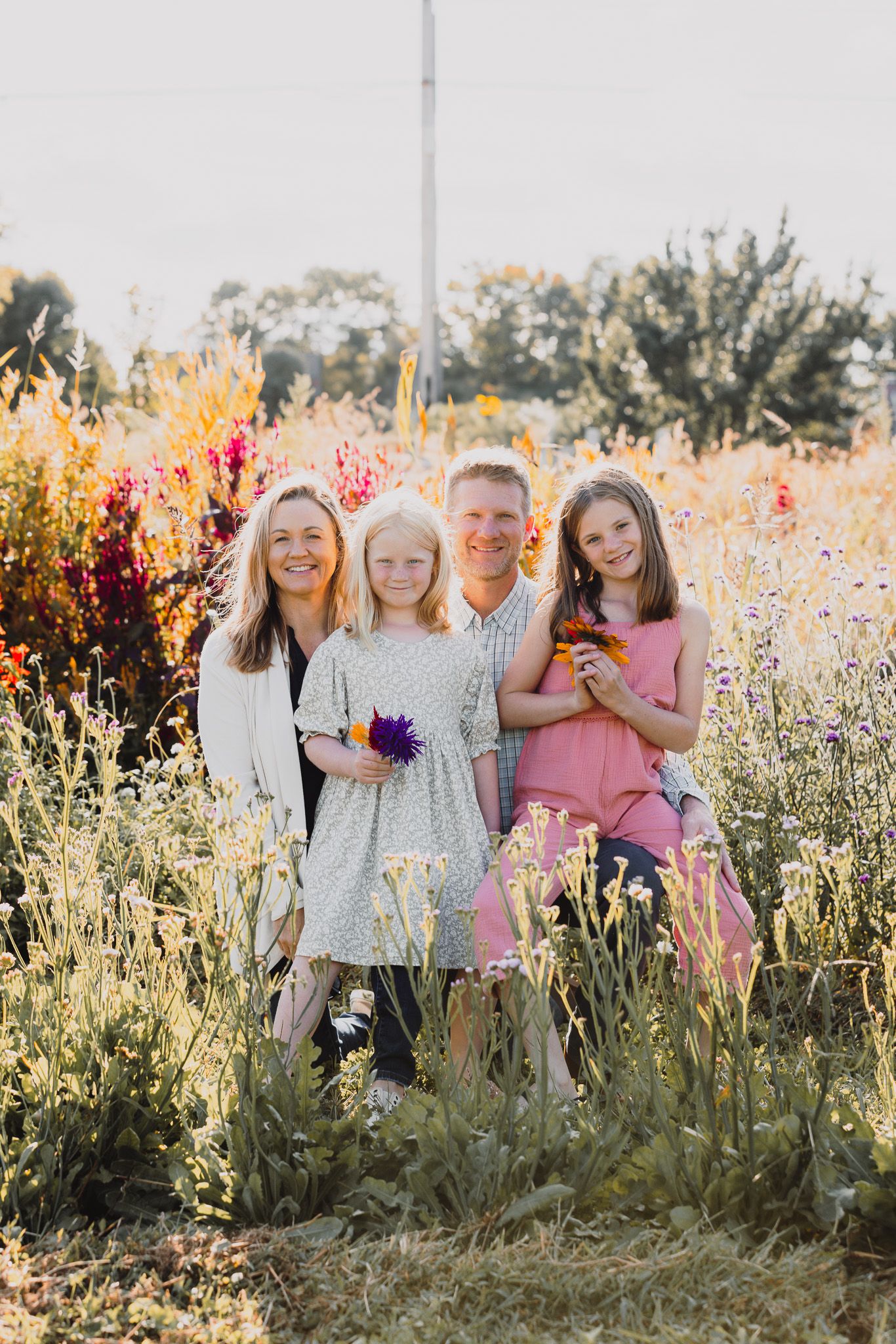 Family portrait in wildflower field during golden hour sunset.