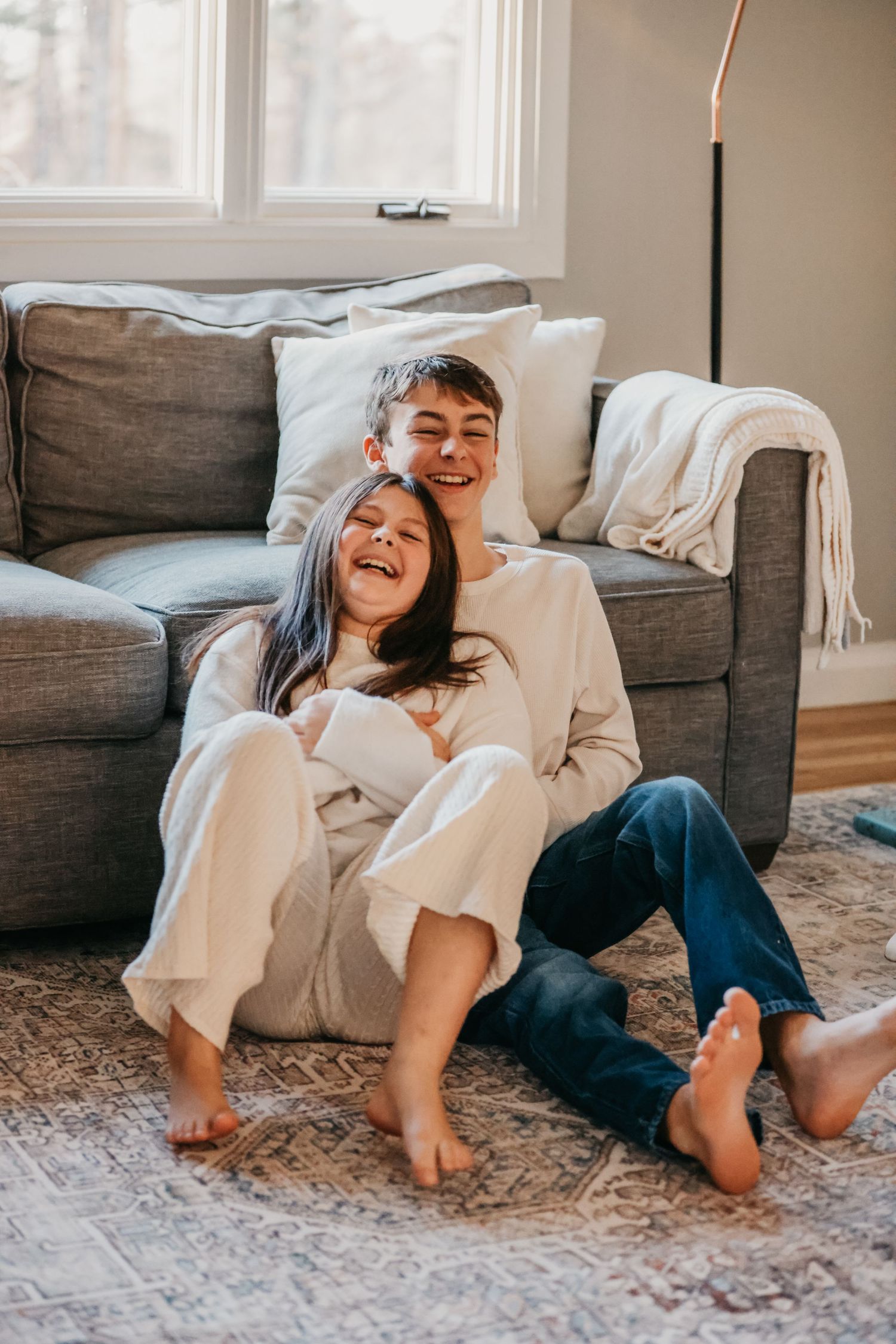 Candid lifestyle photo showing joyful laughter on cozy gray couch.