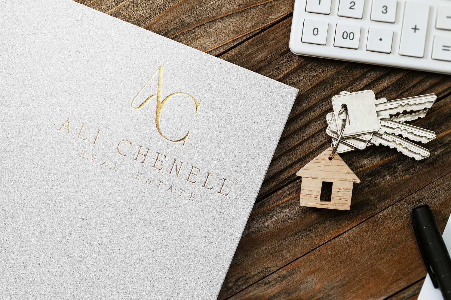 Minimalist business cards and keys arranged on rustic wooden surface with small house decoration.