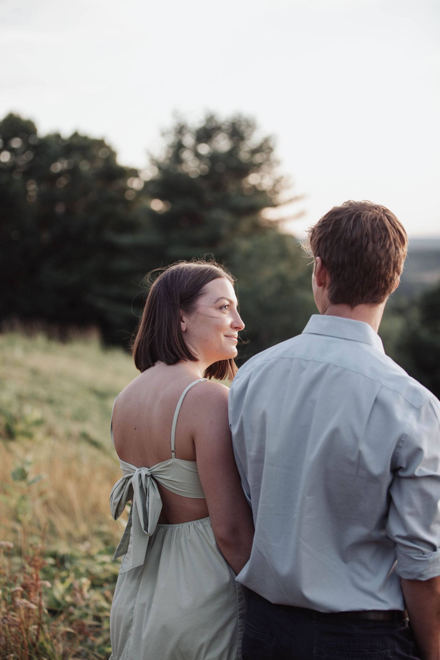 A couple shares an intimate moment while standing in a golden field at sunset.