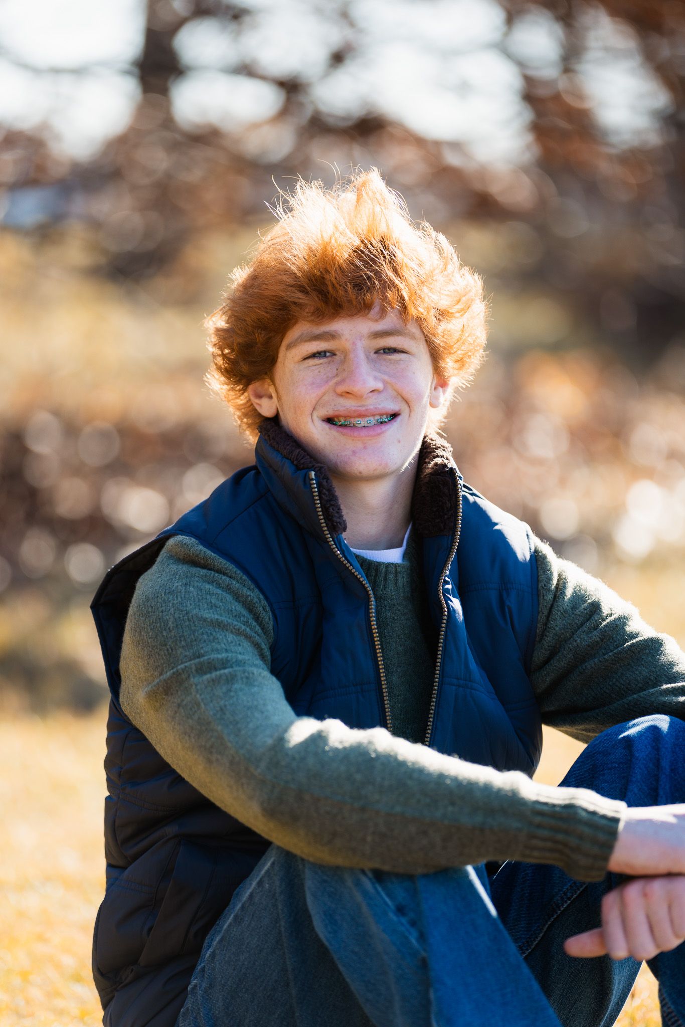 Casual outdoor portrait in warm sunlight showing relaxed pose against natural background.