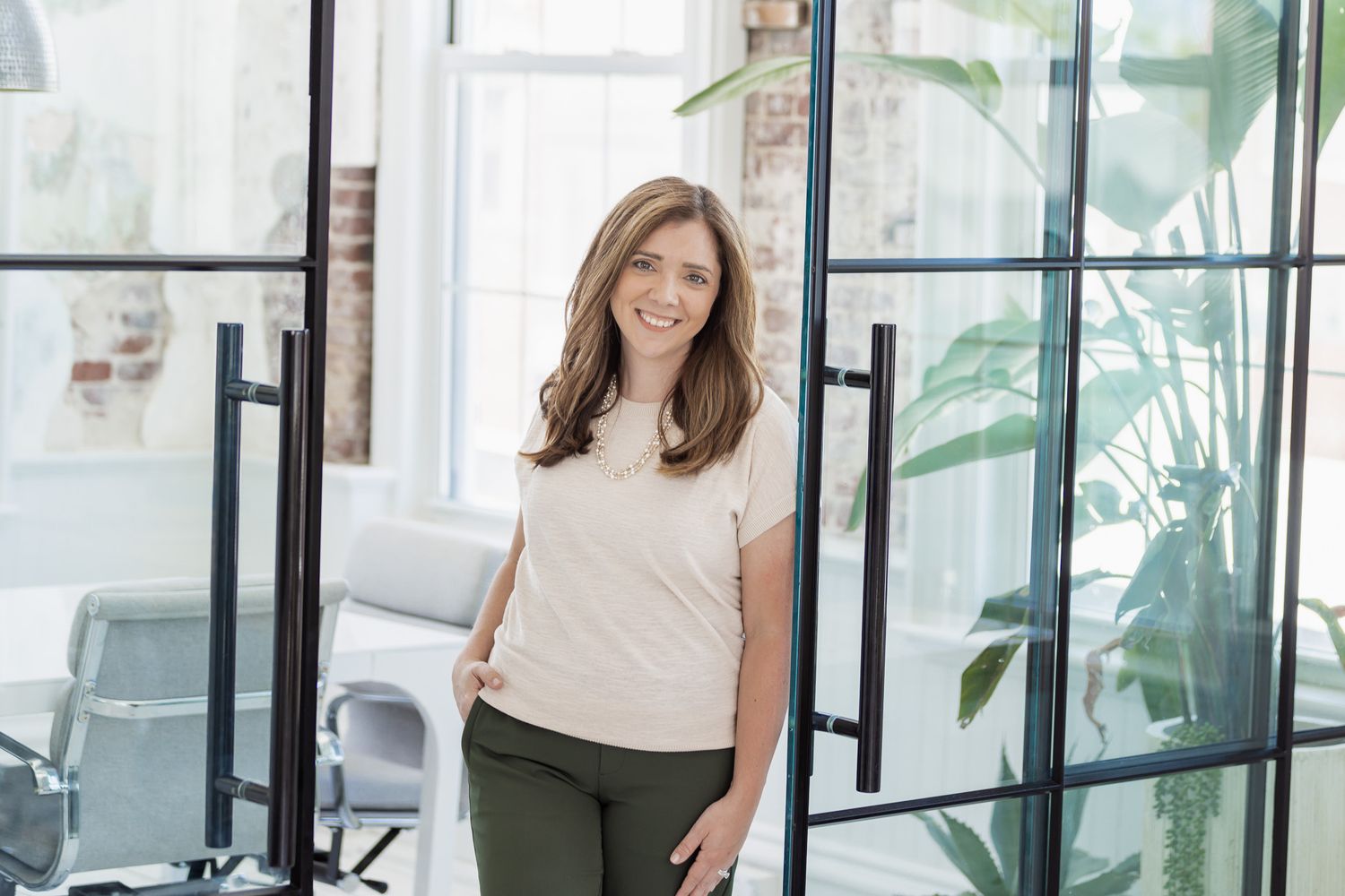 Professional lifestyle portraits in modern office space with glass walls and plants.