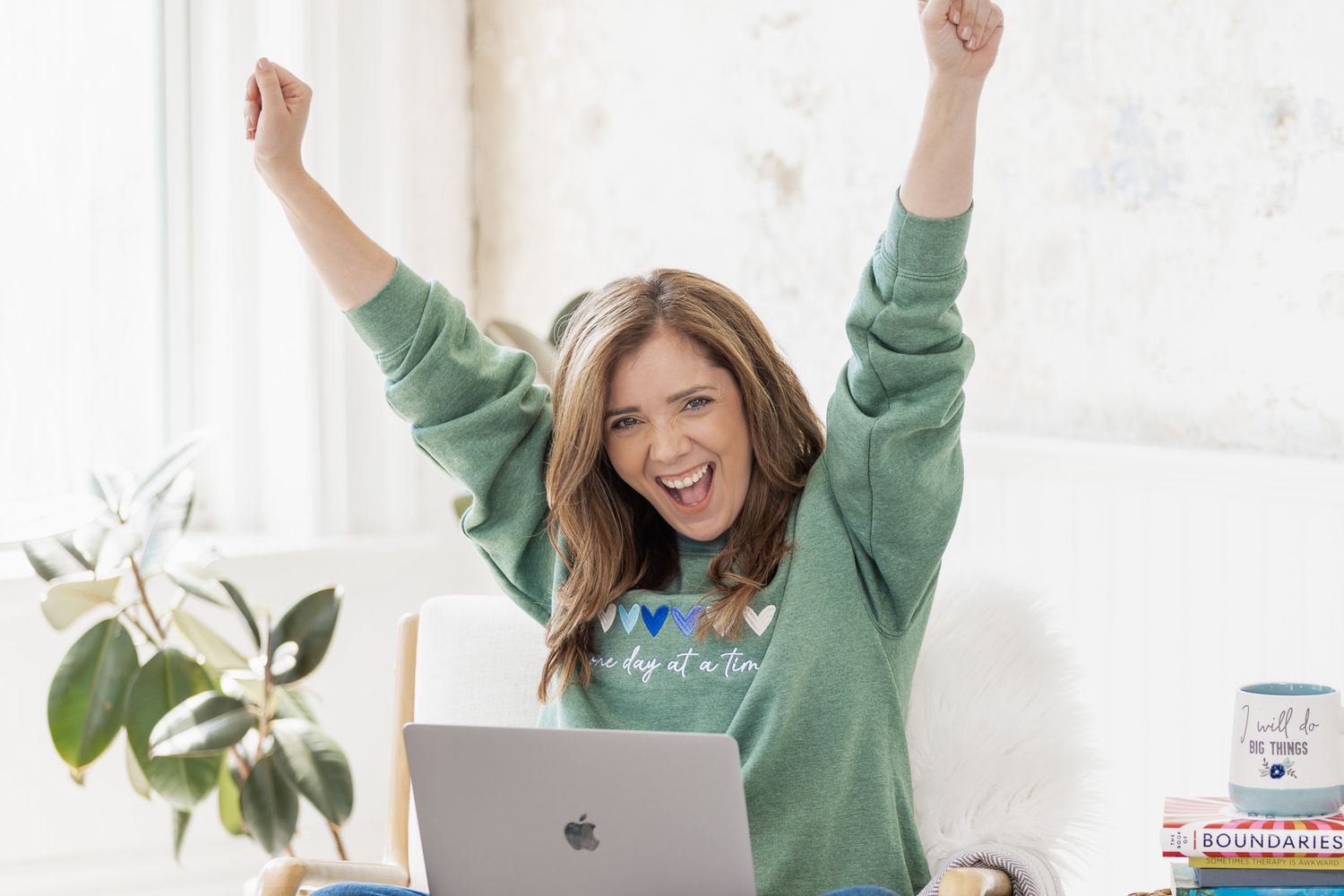 Person in green sweater showing excited poses against white wall.