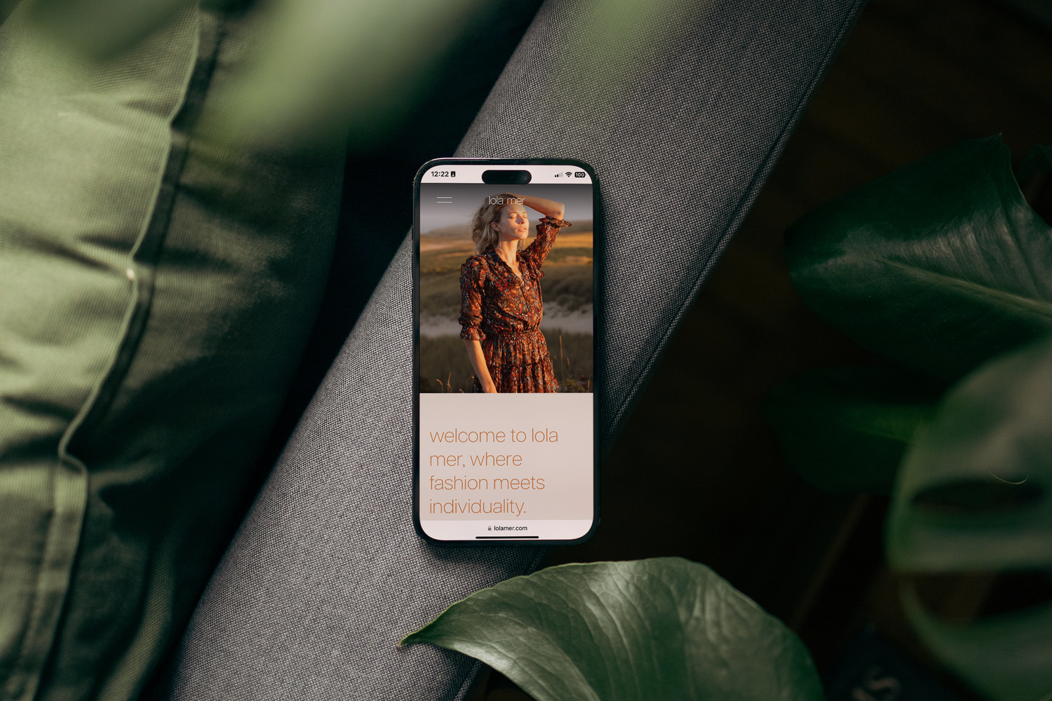 A smartphone displaying a photo lies on a dark surface with green monstera leaves in the frame.