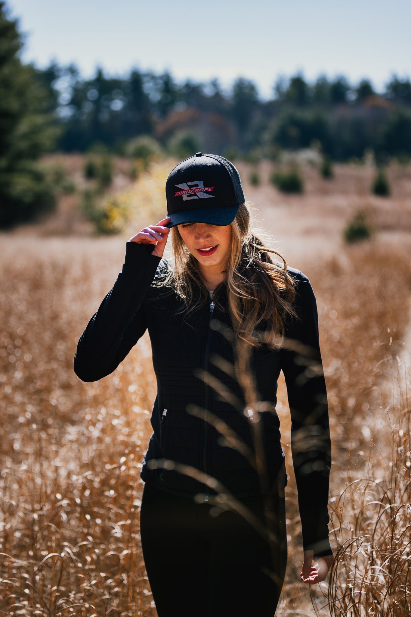 Person in dark clothing walking through a field of tall dried grass.
