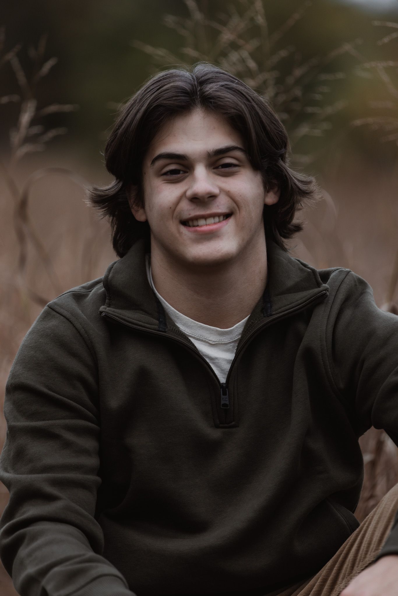 Casual portrait in olive green hoodie showing genuine expression outdoors.