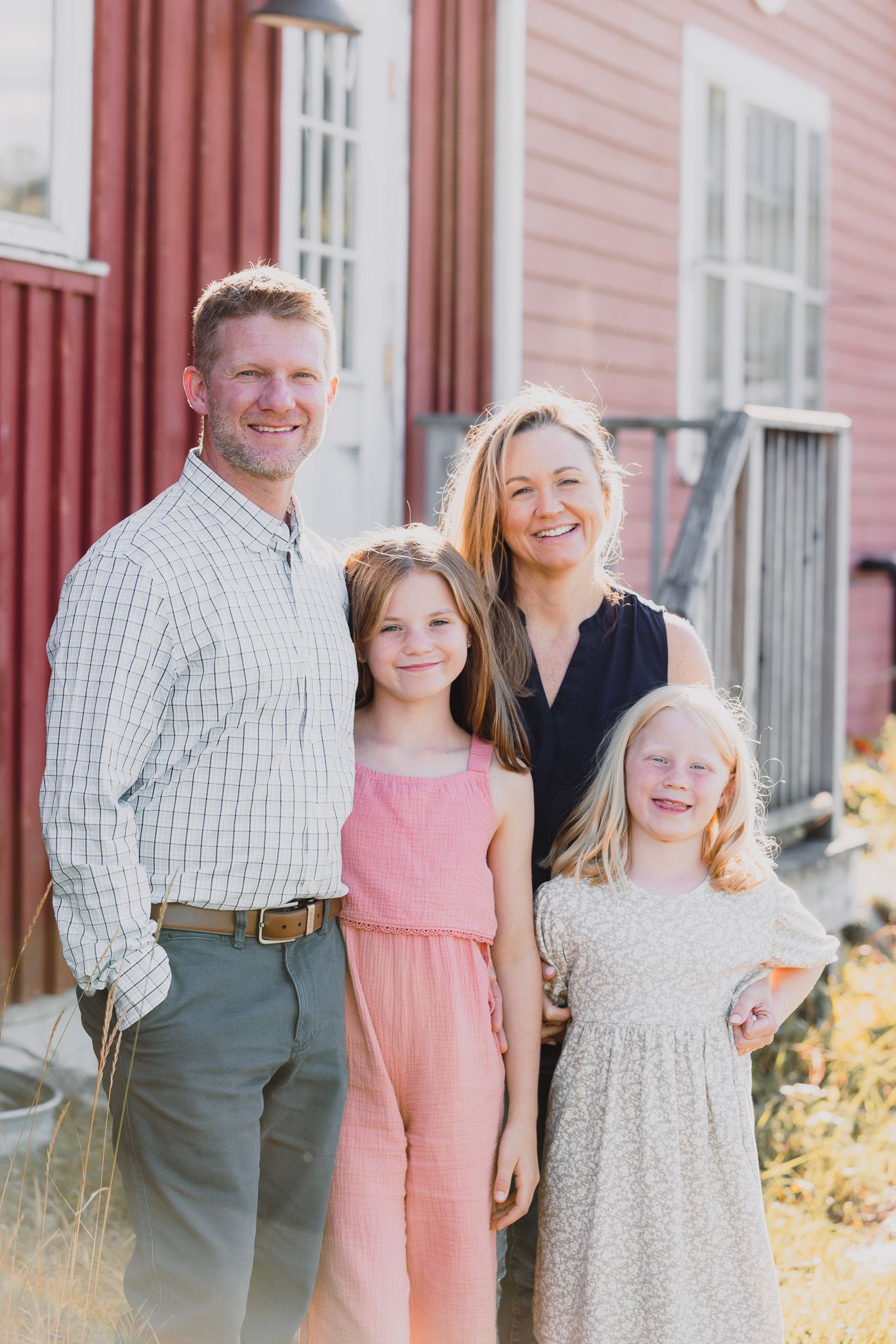 Group portrait against a red farmhouse with white trim windows.