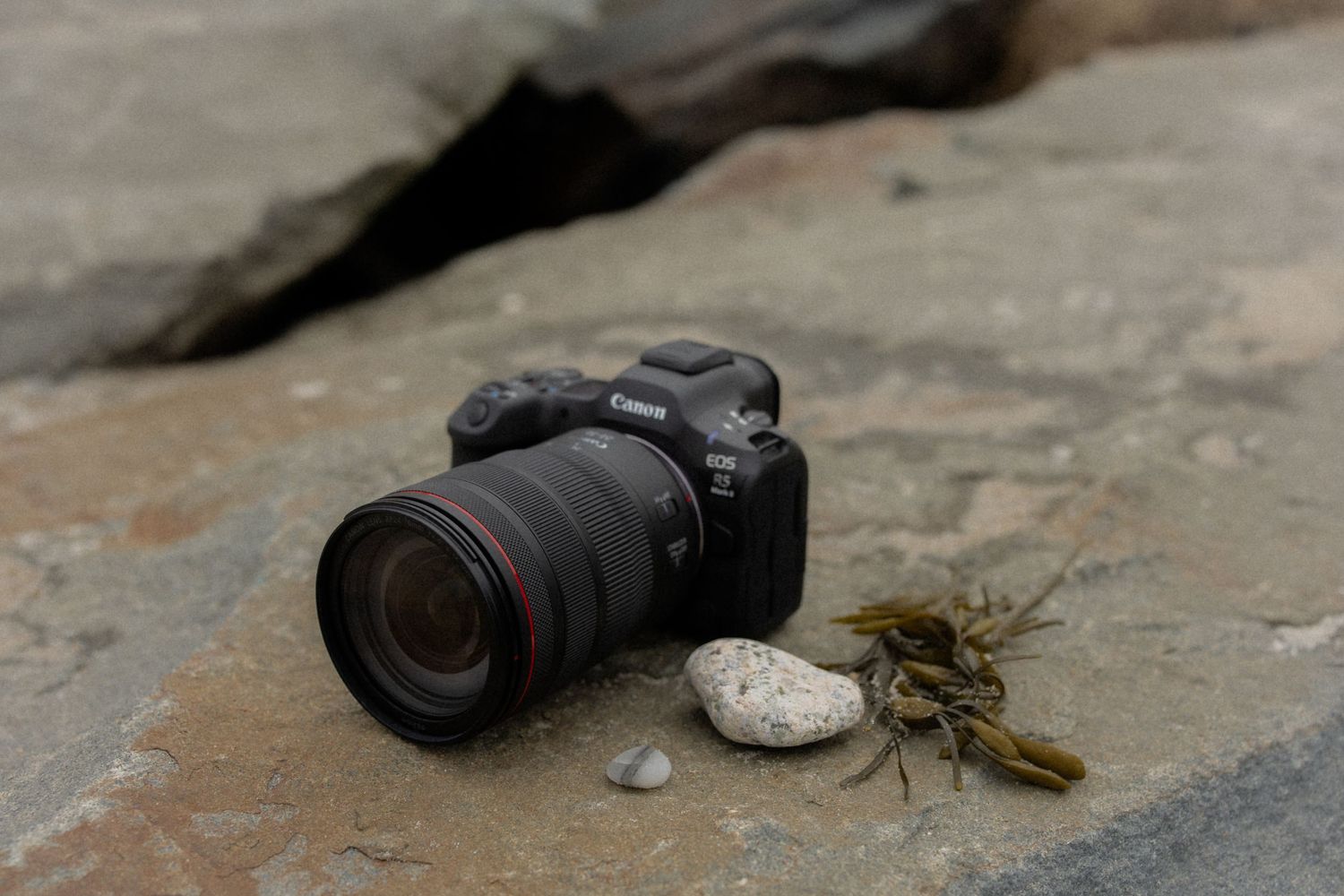 Broken pieces of black camera equipment scattered on rough concrete surface.