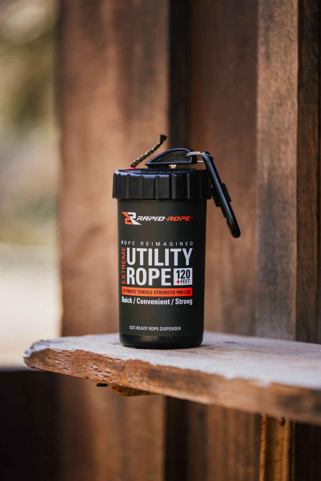 Black utility rope container sitting on wooden surface with blurred background.