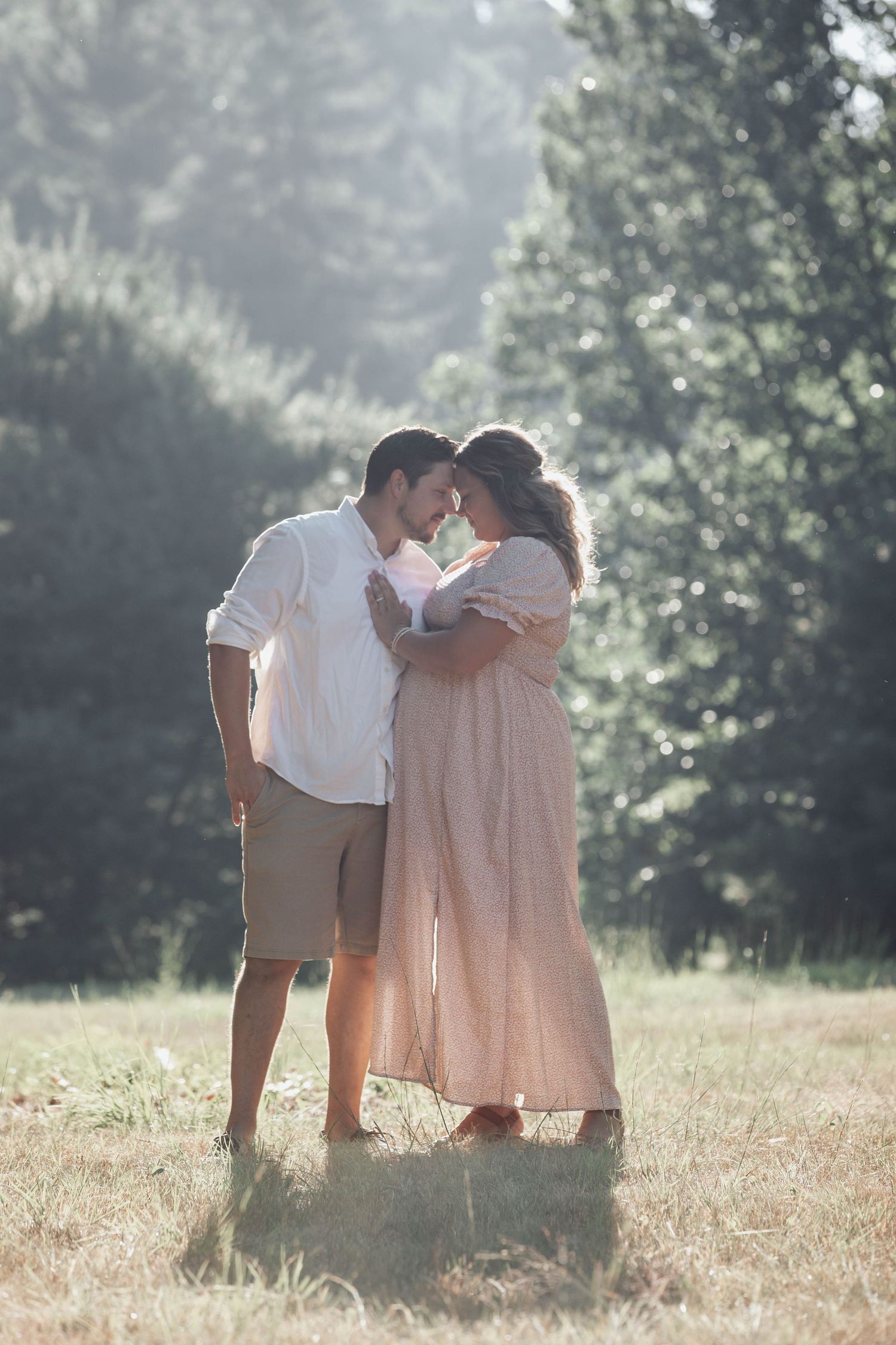 A romantic couple sharing intimate moments in a sunlit meadow during golden hour.