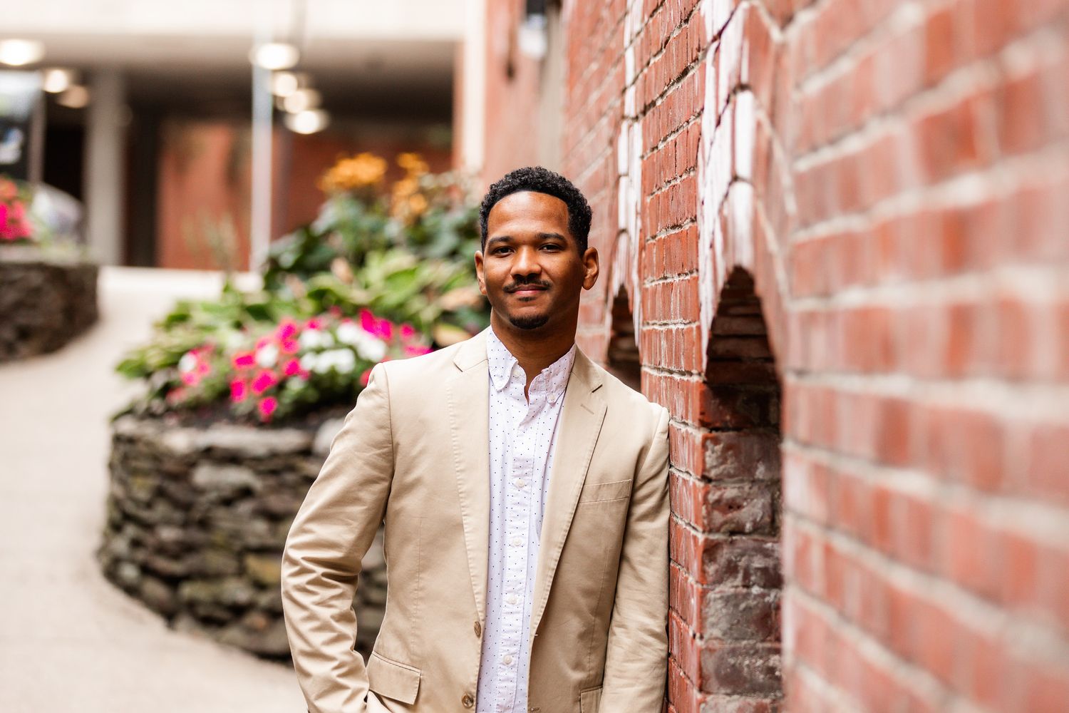 Urban portraits of someone in professional attire posing against red brick walls.