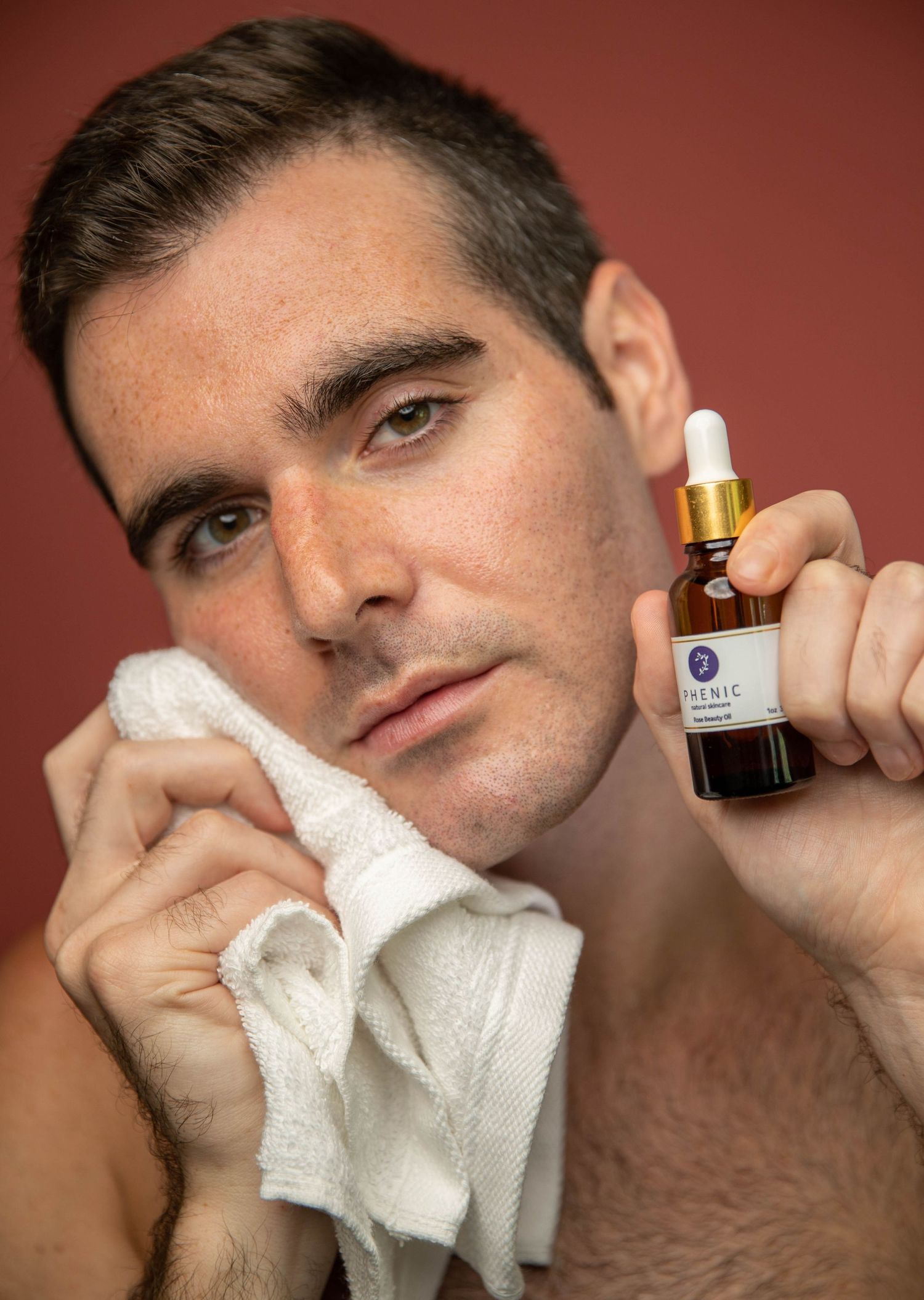 Lifestyle product shot with essential oil bottle and white towel.