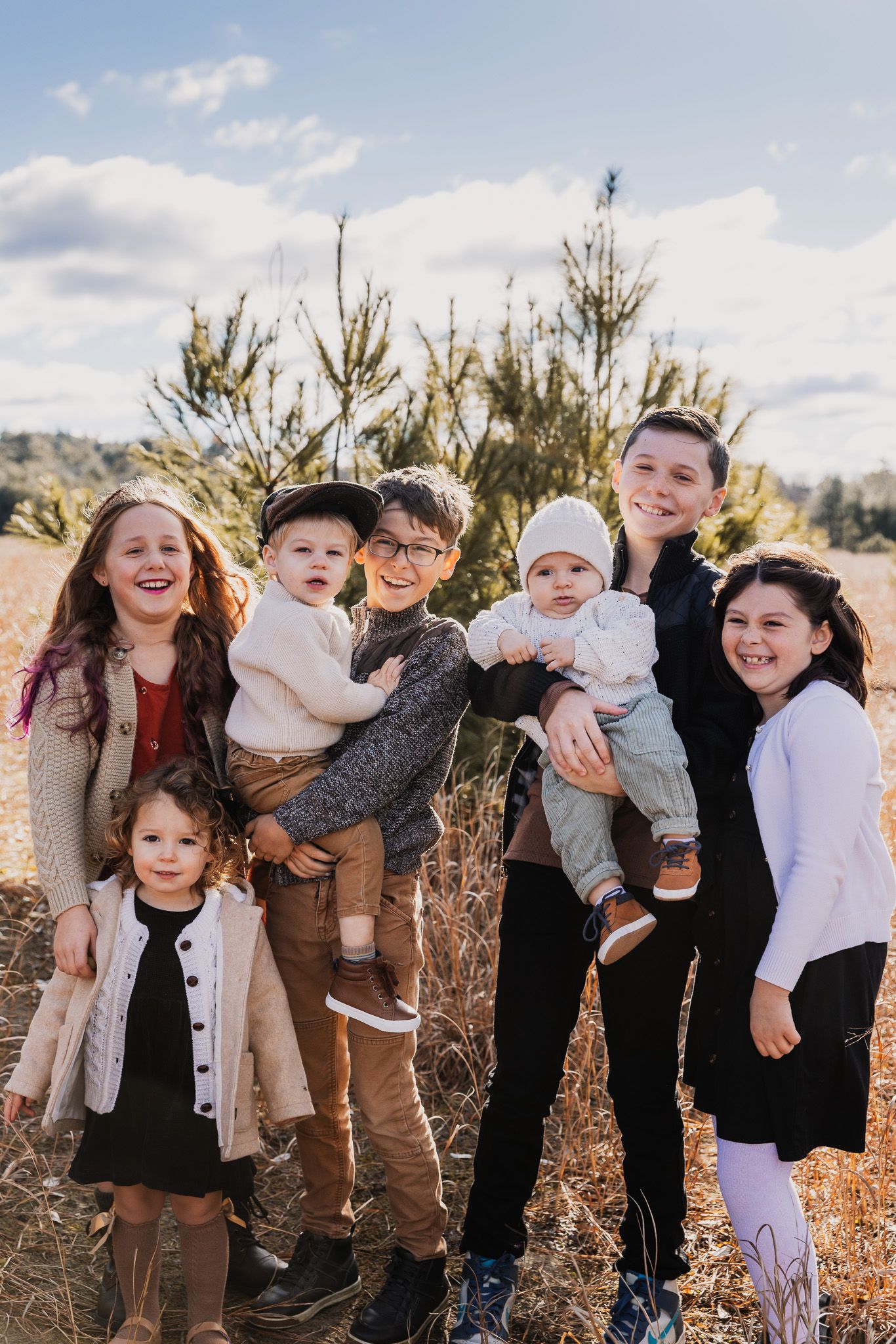 Cheerful group portrait in natural setting with pine trees and autumn colors.