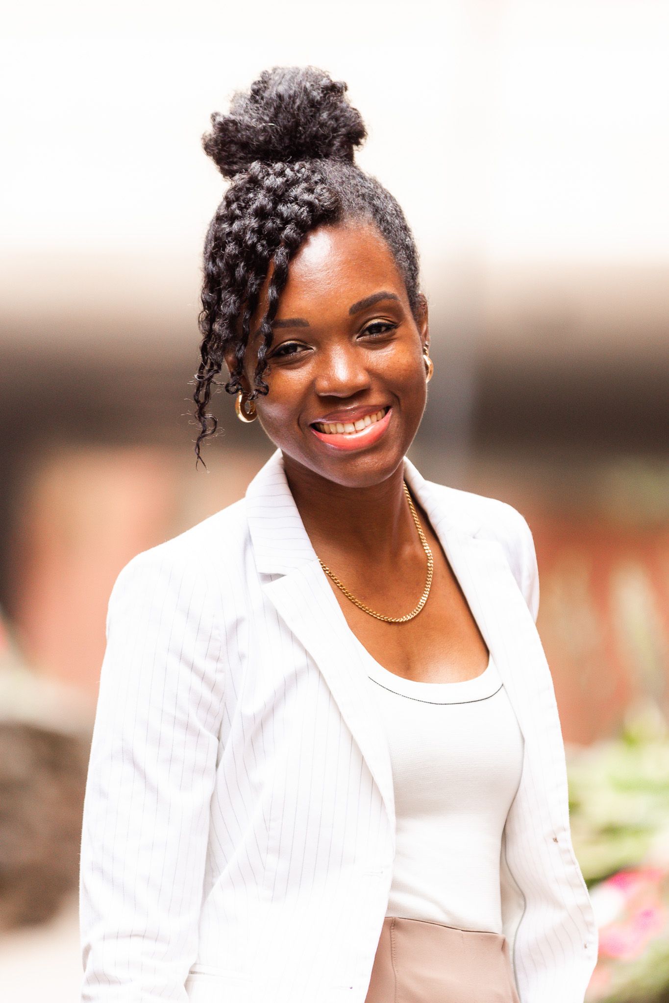 Professional headshots of a person in white business attire smiling against a blurred background.
